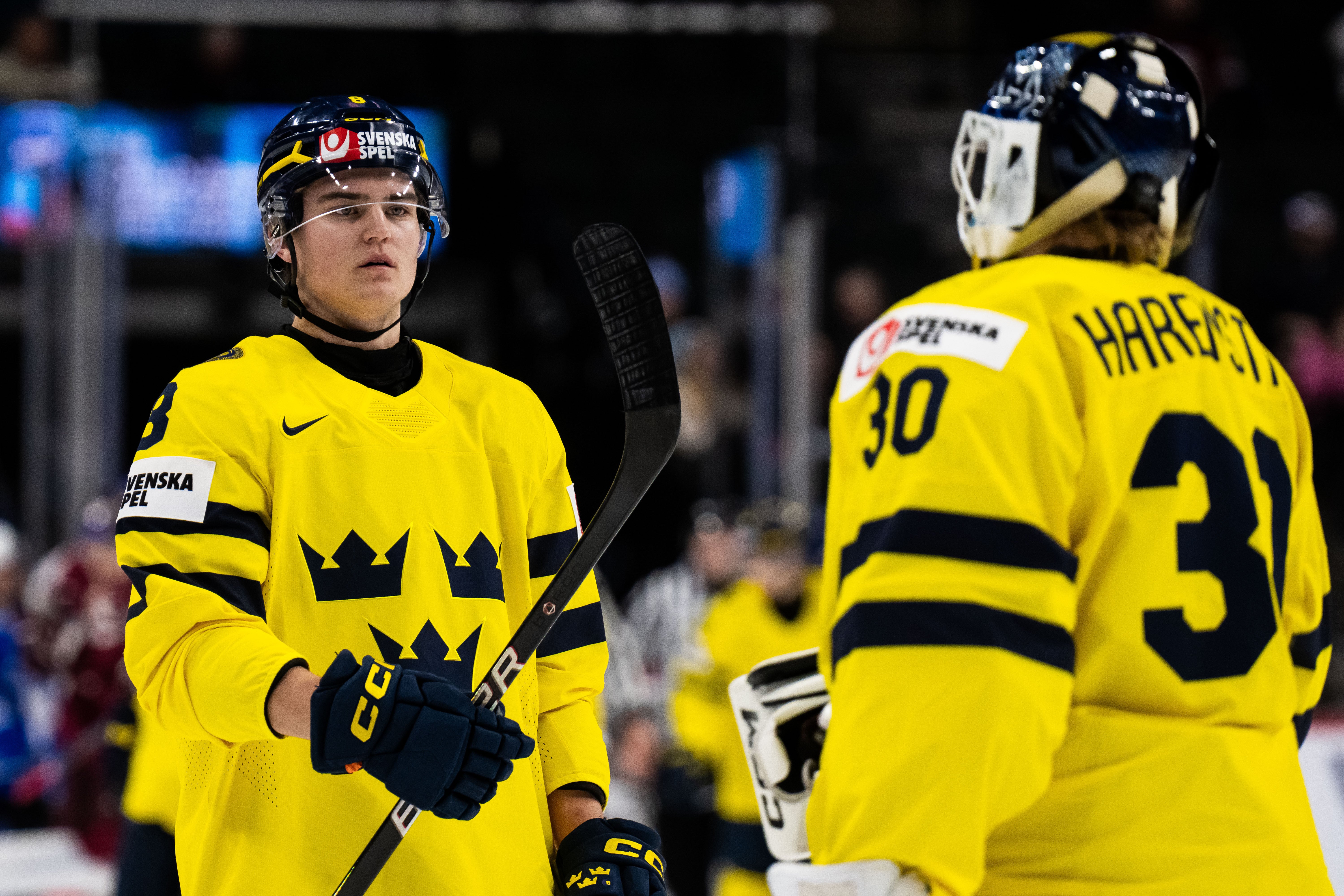 Två ishockeyspelare i gula och svarta landslagströjor under en match. Spelaren till vänster bär nummer 68 och spelaren till höger bär nummer 30 med namnet Härär på ryggen.