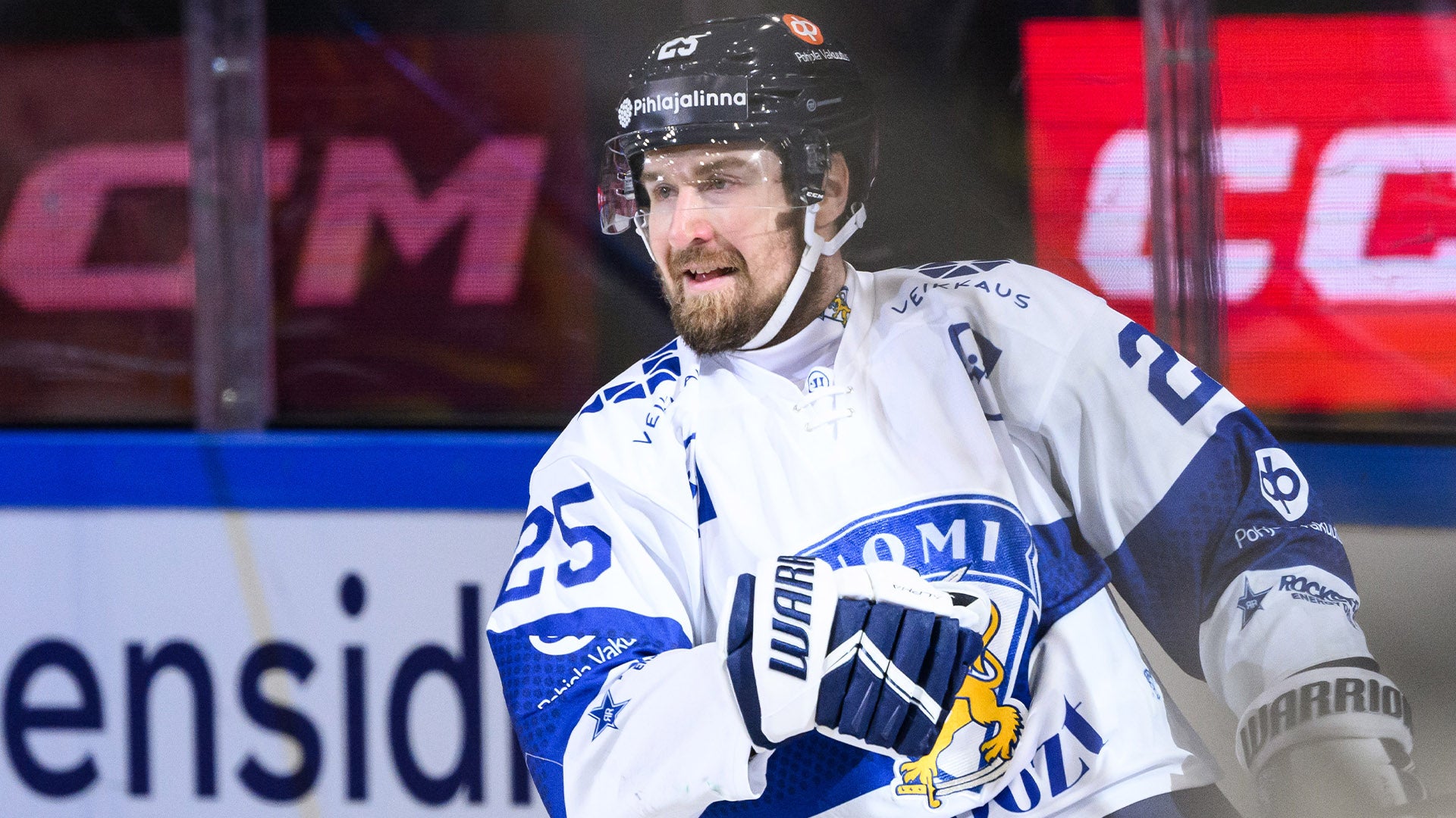 Ishockeyspelare i vit och blå tröja under en match. Spelaren bär hjälm och är på isen under spel.