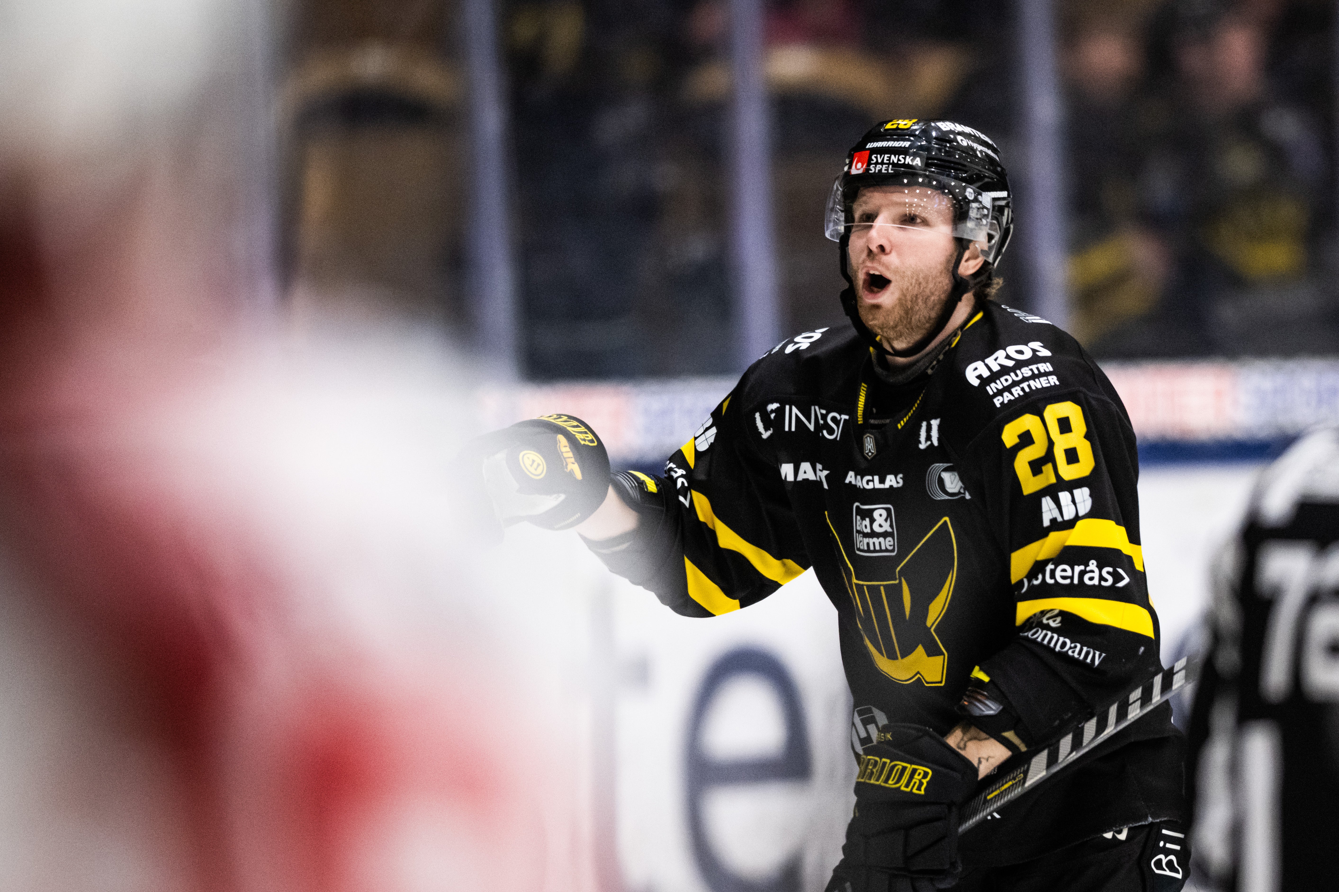 Ishockeyspelare i svart och gul matchdräkt med nummer 28 under en ishockeymatch.