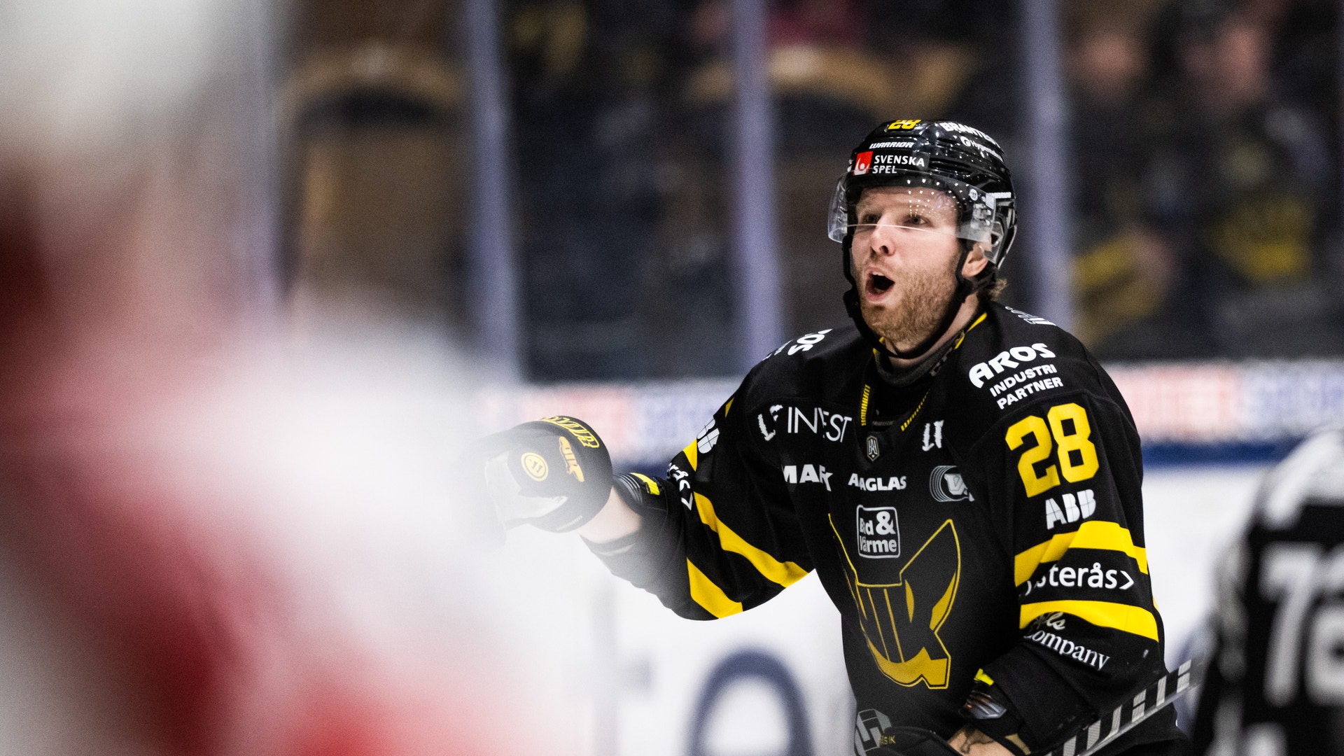 Ishockeyspelare i svart och gul matchdräkt med nummer 28 under en ishockeymatch.