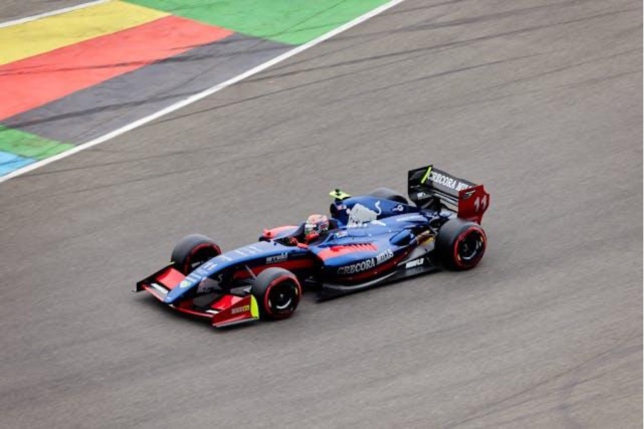 En blå och röd Formel 1-bil kör på en racerbana med färgade markeringar längs kanten.