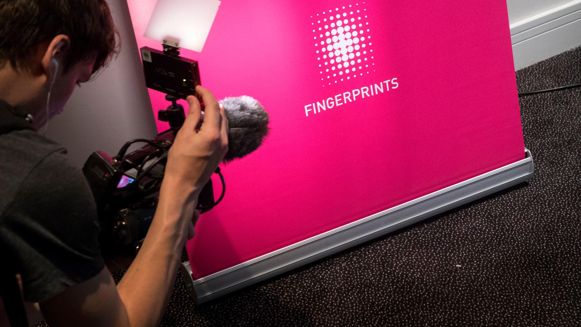 Person filmar en rosa vägg med Fingerprints-logotyp och text.