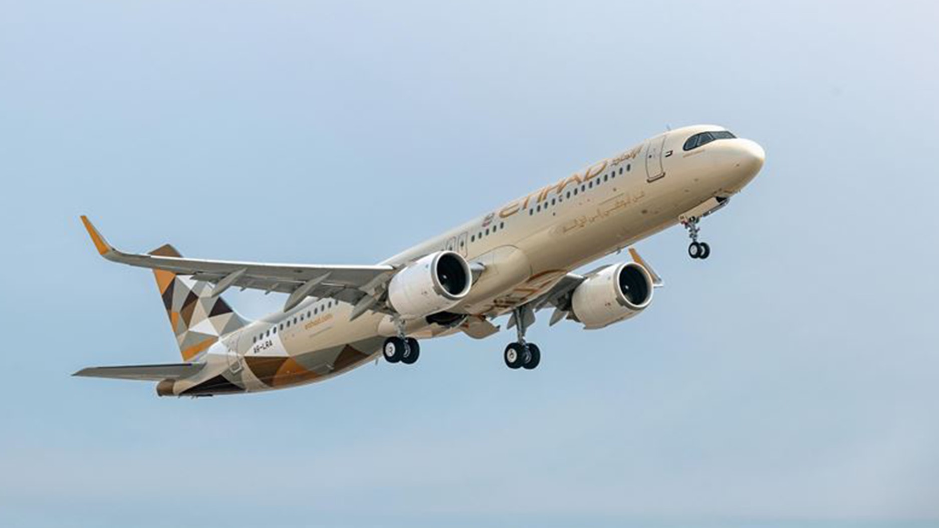 Ett Etihad Airways-flygplan i luften mot en klar blå himmel. Planet har vit och guldbrunt färgschema.