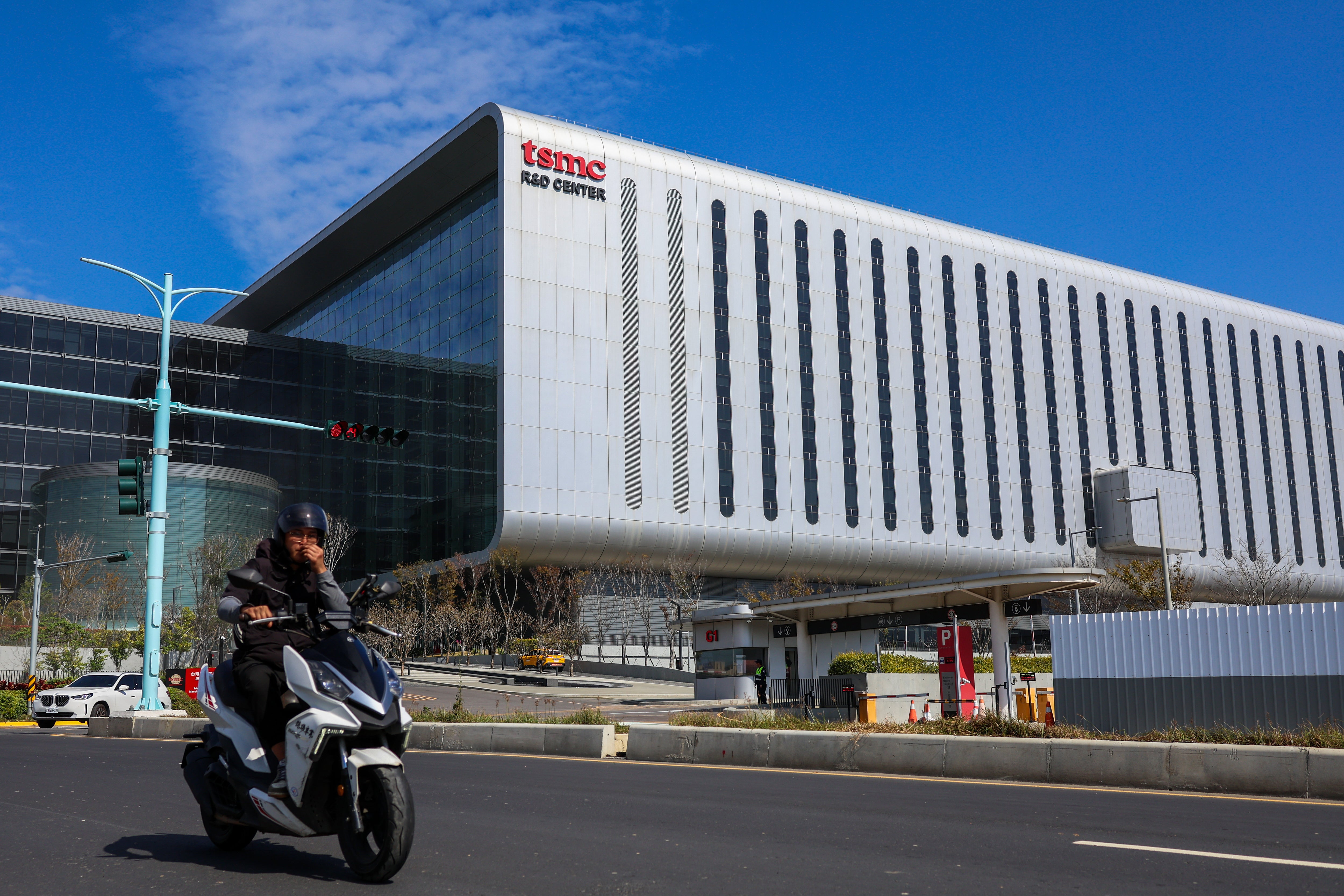 En person på en svart scooter framför en modern vit byggnad med DATA CENTER-skylt.