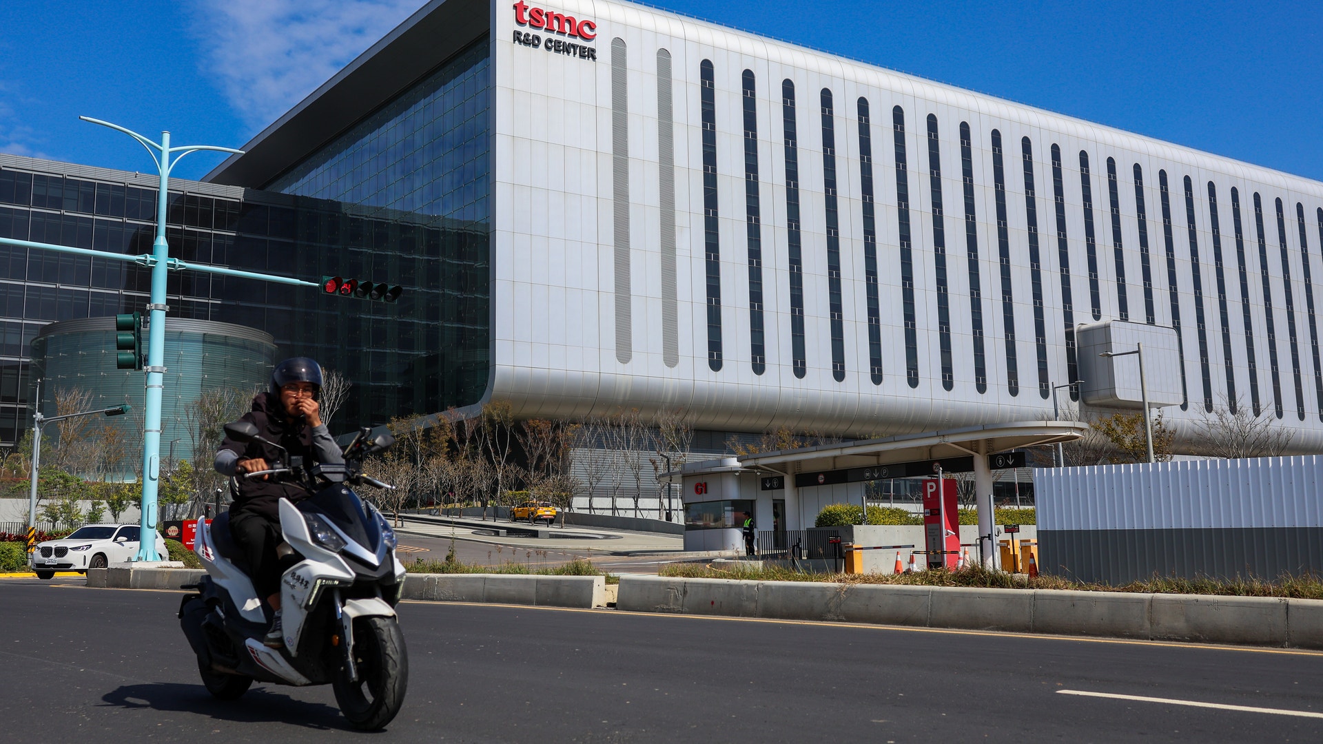 En person på en svart scooter framför en modern vit byggnad med DATA CENTER-skylt.