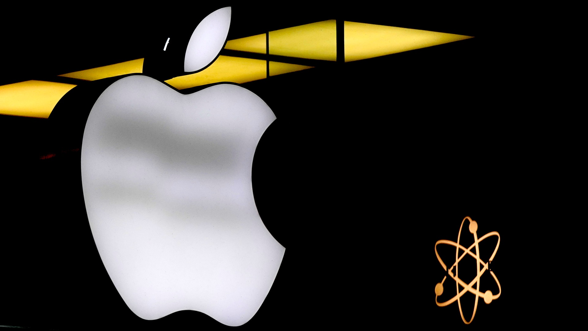 Apples logotyp - ett vitt äpple - tillsammans med en gul penna och en orange atom-symbol på svart bakgrund, som representerar teknik och innovation.