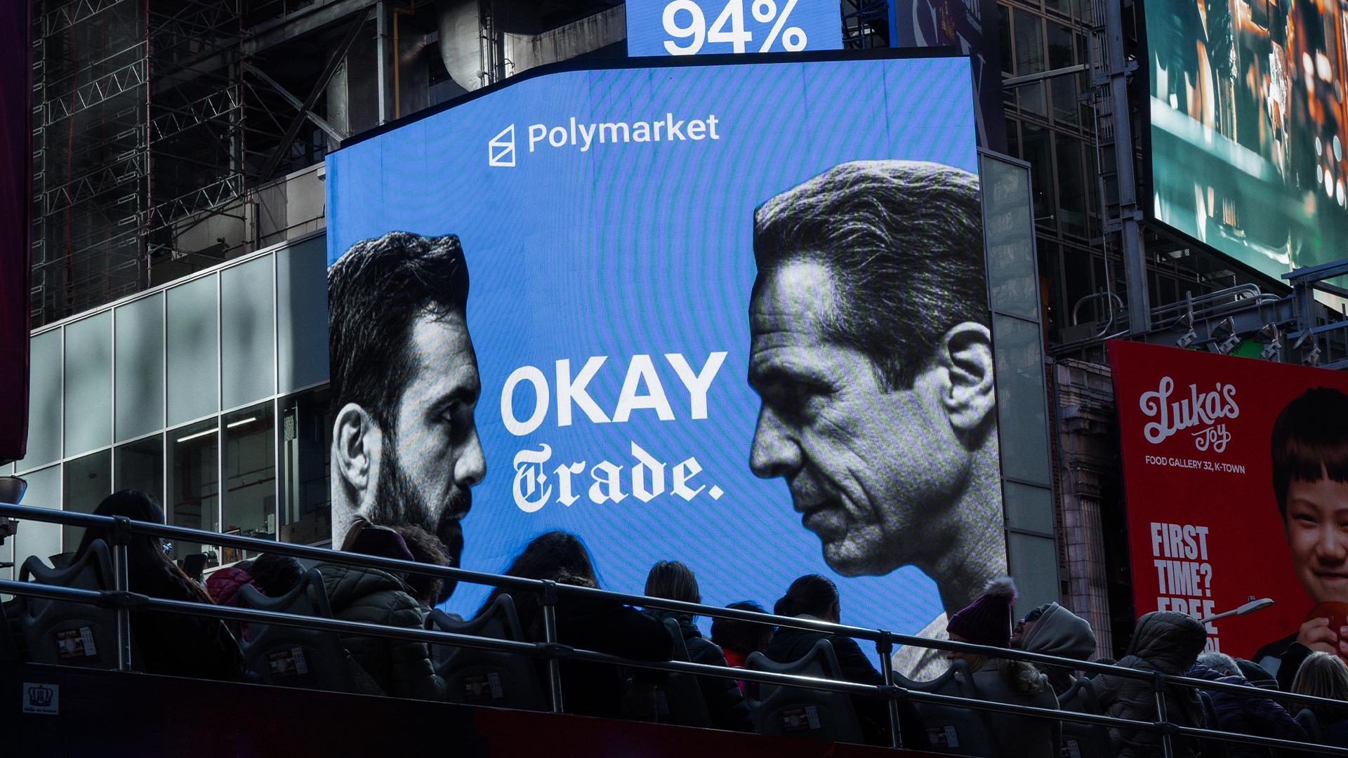 Stor blå reklamaffisch för Polymarket med två mäns ansikten i profil och texten "OKAY trade"