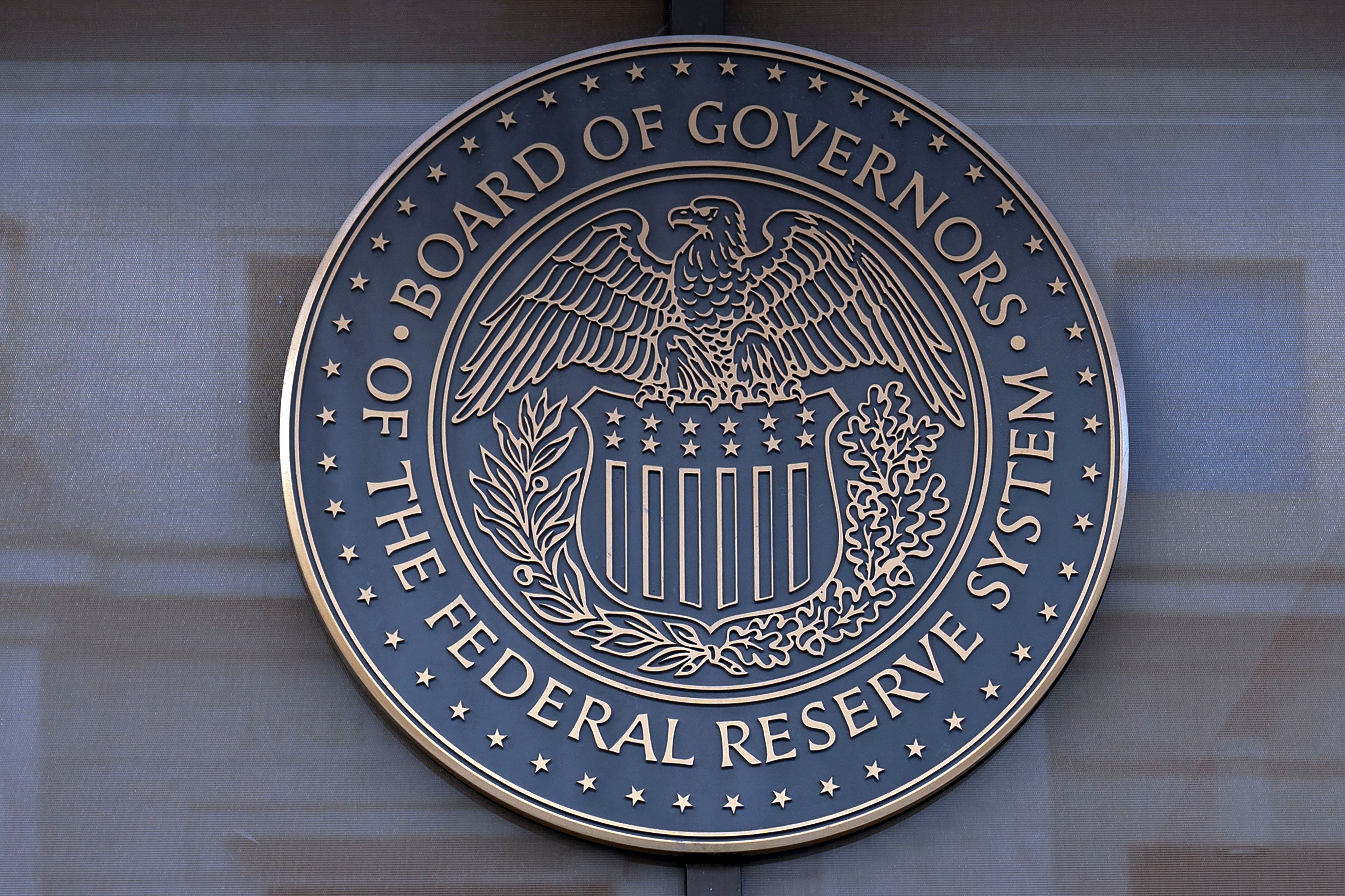 Rund bronsskylt med USA:s centralbanks sigill, en örn med sköld, och texten "Board of Governors of the Federal Reserve System".