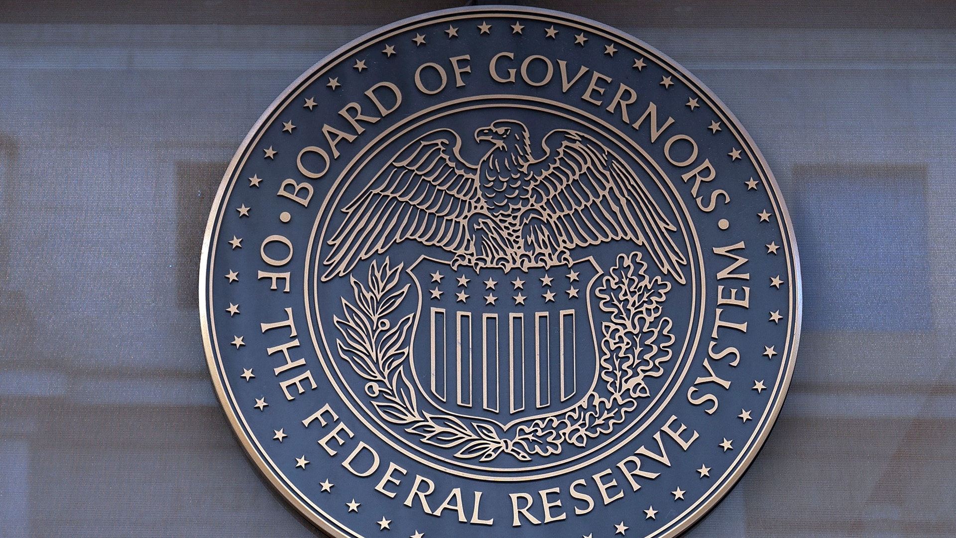Rund bronsskylt med USA:s centralbanks sigill, en örn med sköld, och texten "Board of Governors of the Federal Reserve System".