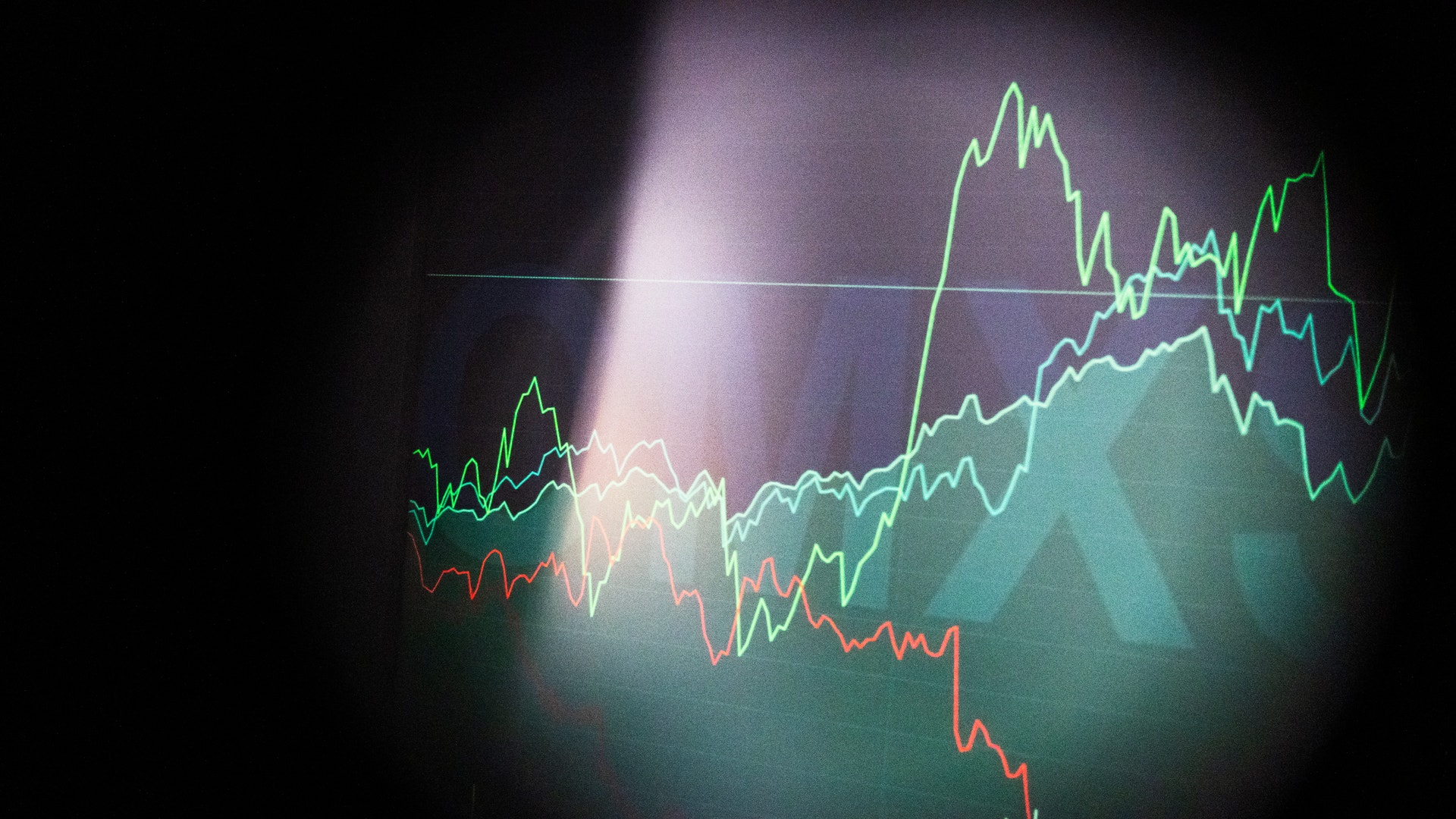 Finansiell graf med flera färgade trendlinjer som visar aktiekurser eller marknadsdata över tid på mörk bakgrund.