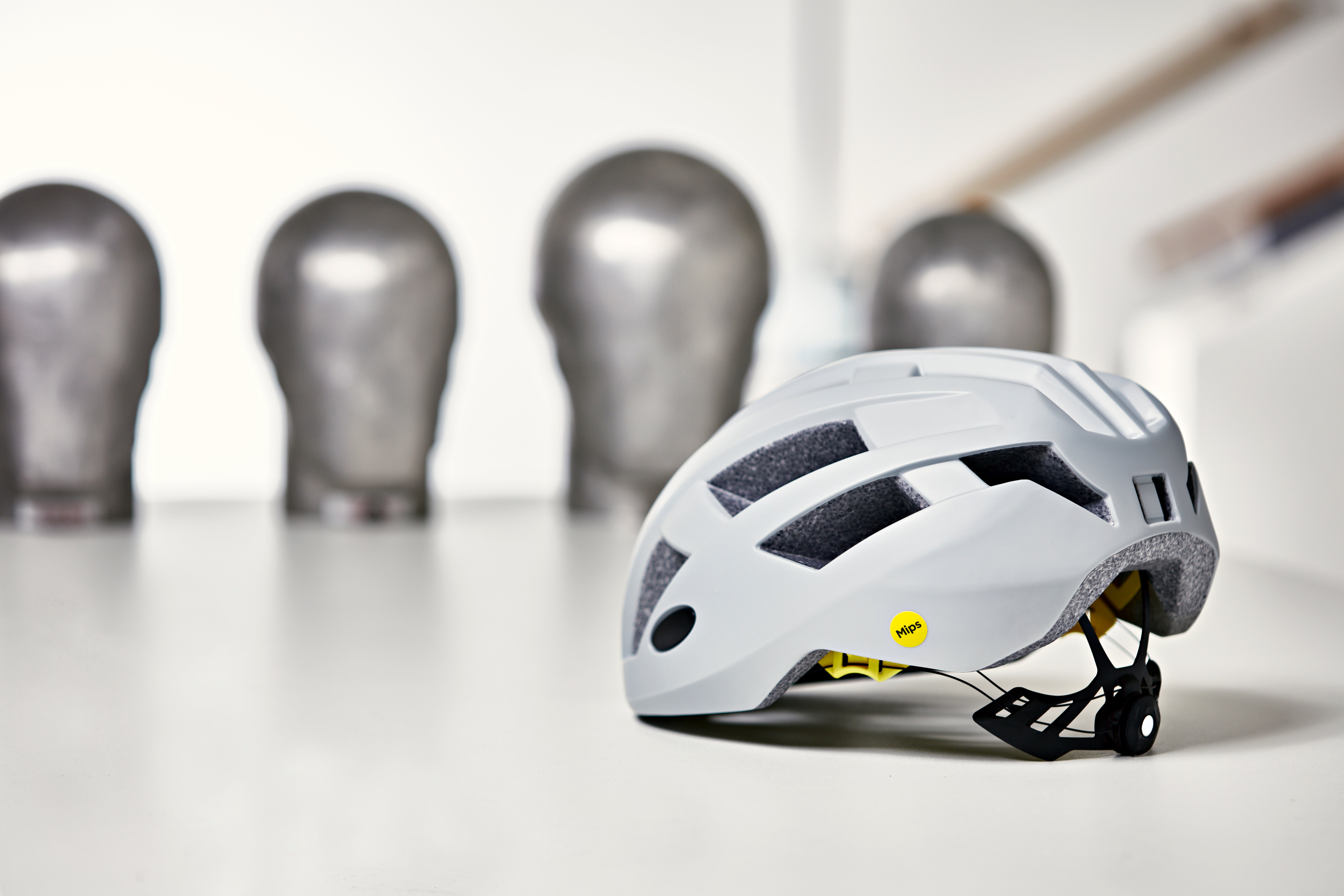 En vit cykelhjälm med svart ventilation och gula detaljer, fotograferad i en testlaboratorium.
