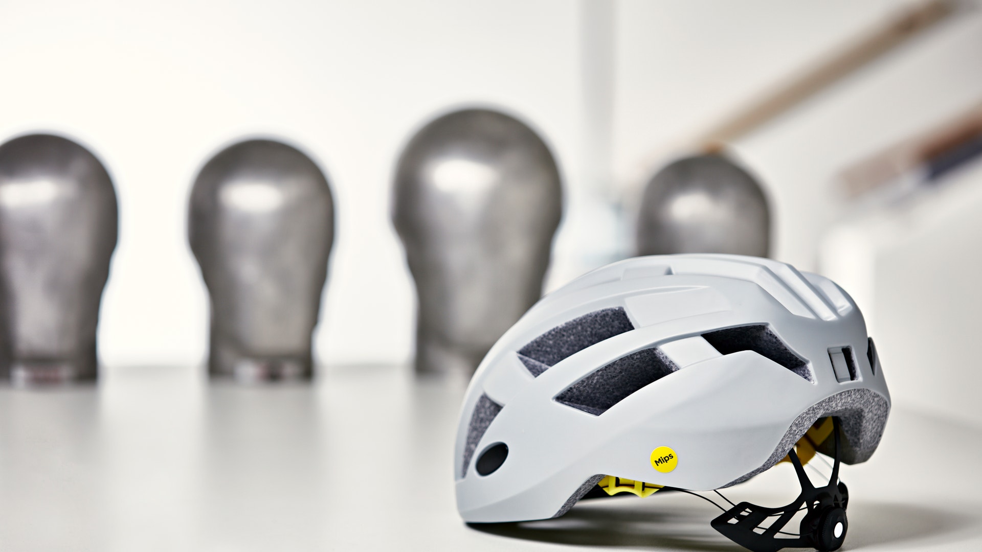 En vit cykelhjälm med svart ventilation och gula detaljer, fotograferad i en testlaboratorium.