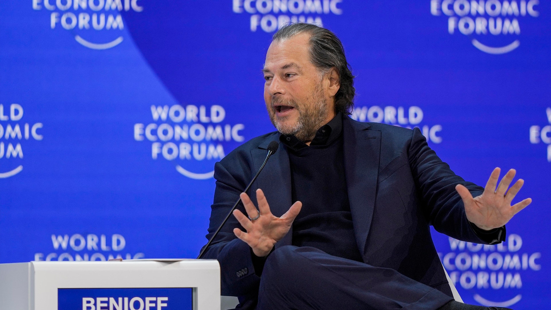 En man talar vid World Economic Forum och gestikulerar medan han presenterar.