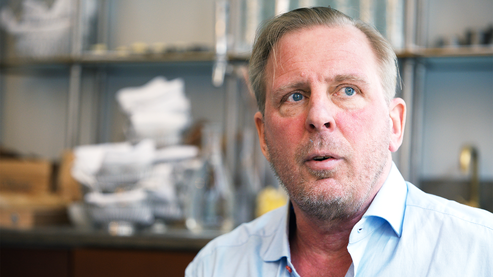 Porträtt av en man i ljusblå skjorta framför en bokhylla