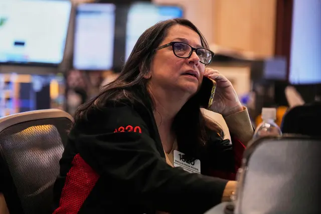 En person med glasögon sitter i en kontorsmiljö och lyssnar uppmärksamt.