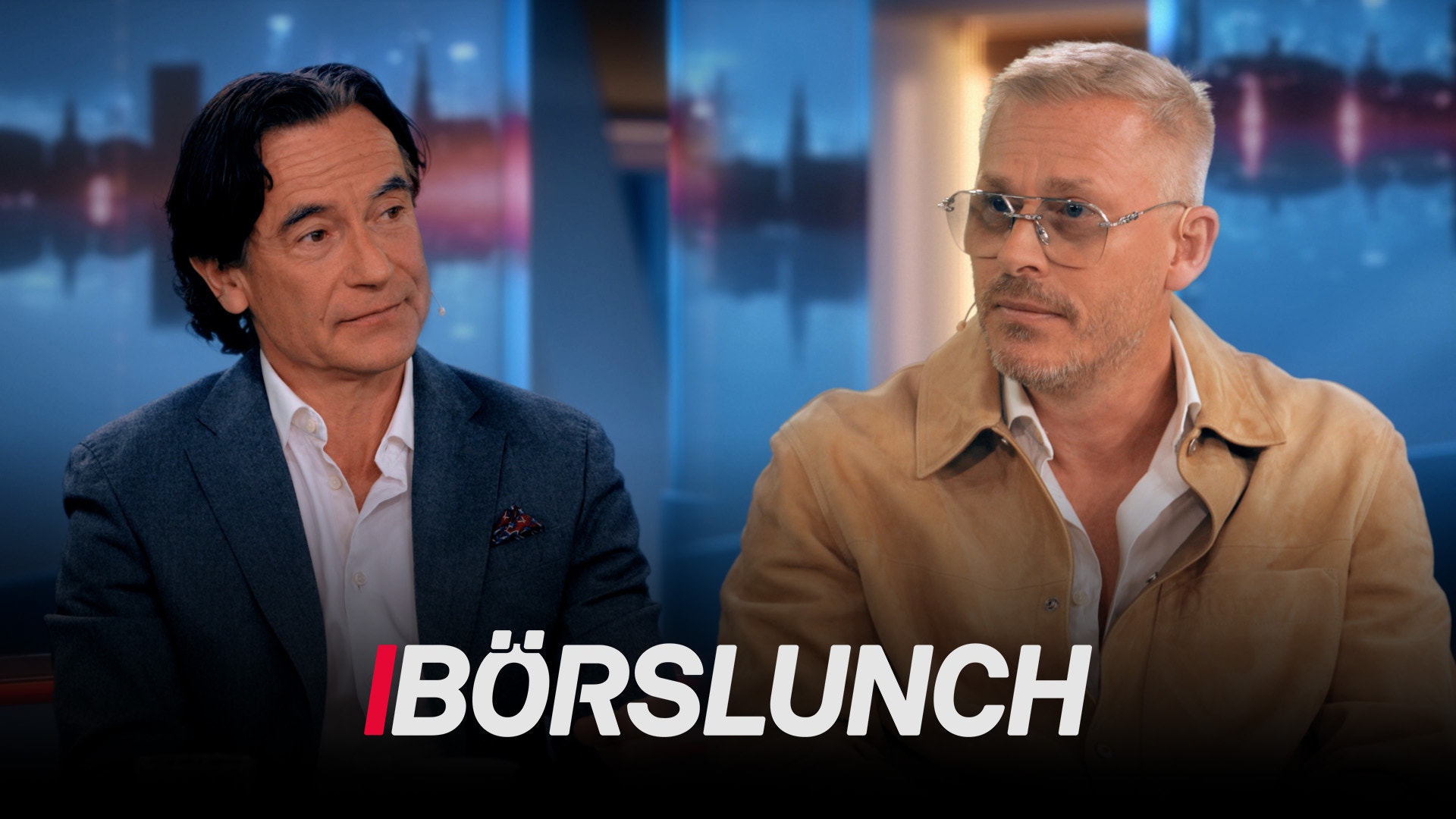 Två män i studiomiljö framför stadsutsikt. Text visar "BÖRSLUNCH".