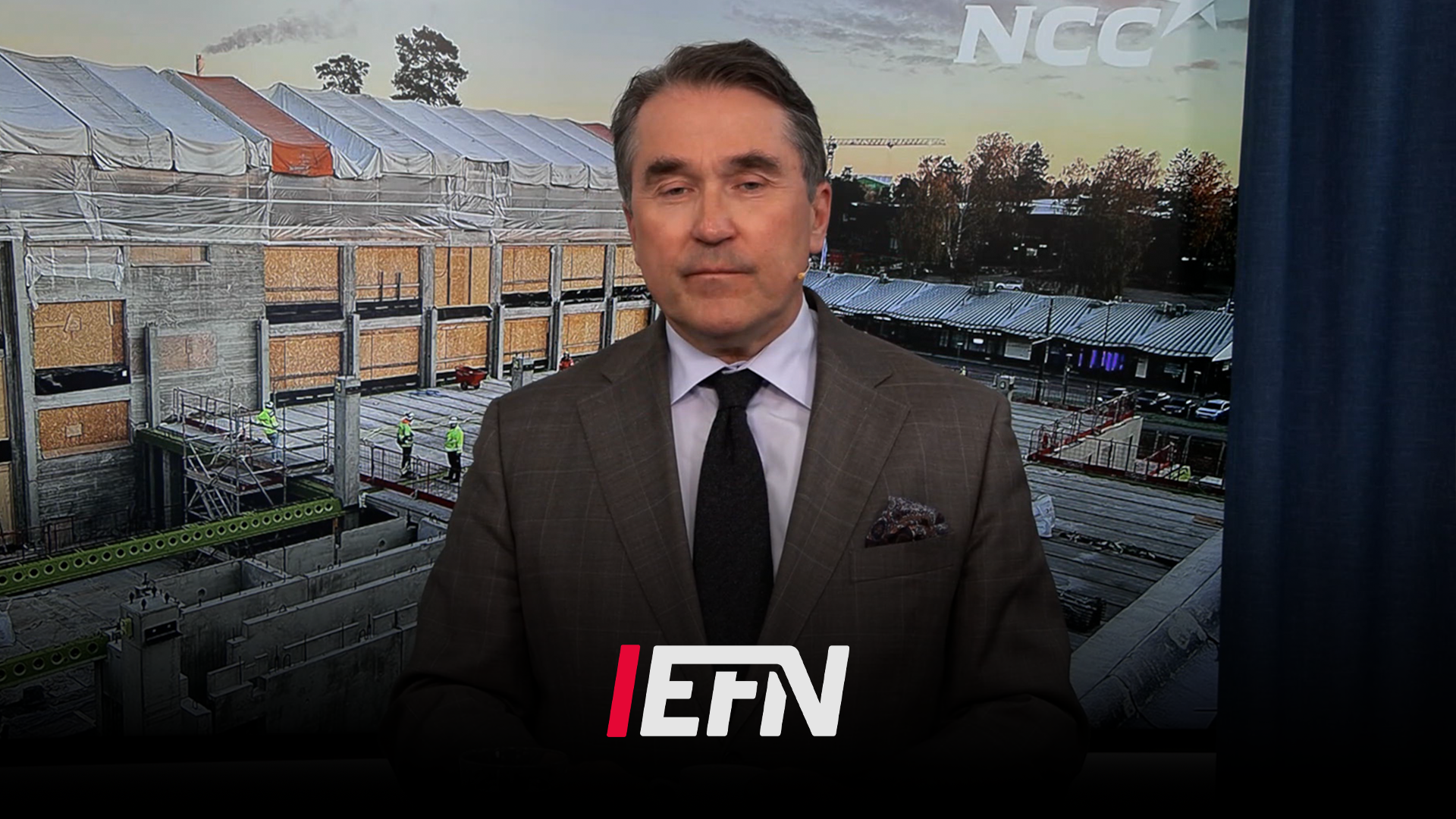 Man i kostym framför en modern byggnad med NCC-logotyp