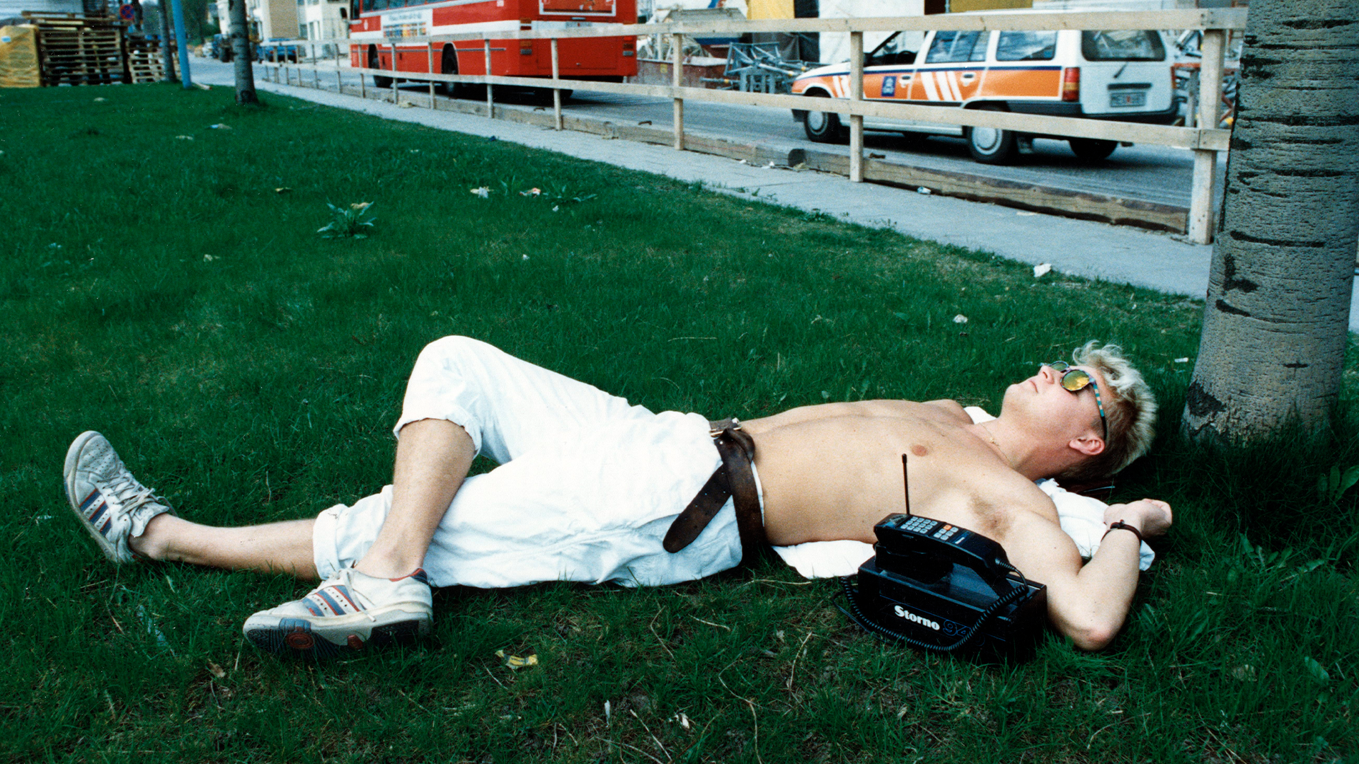 En person ligger avslappnad på gräsmattan vid ett träd