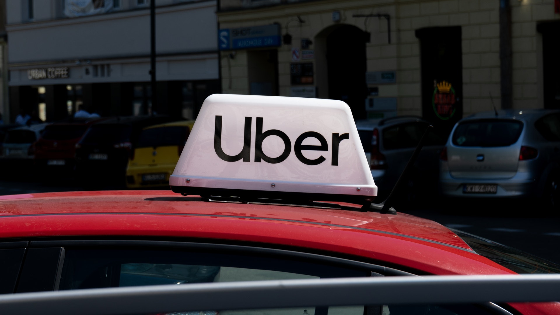En röd Uber-taxi med vitt märke på taket, parkerad på en stadsgata