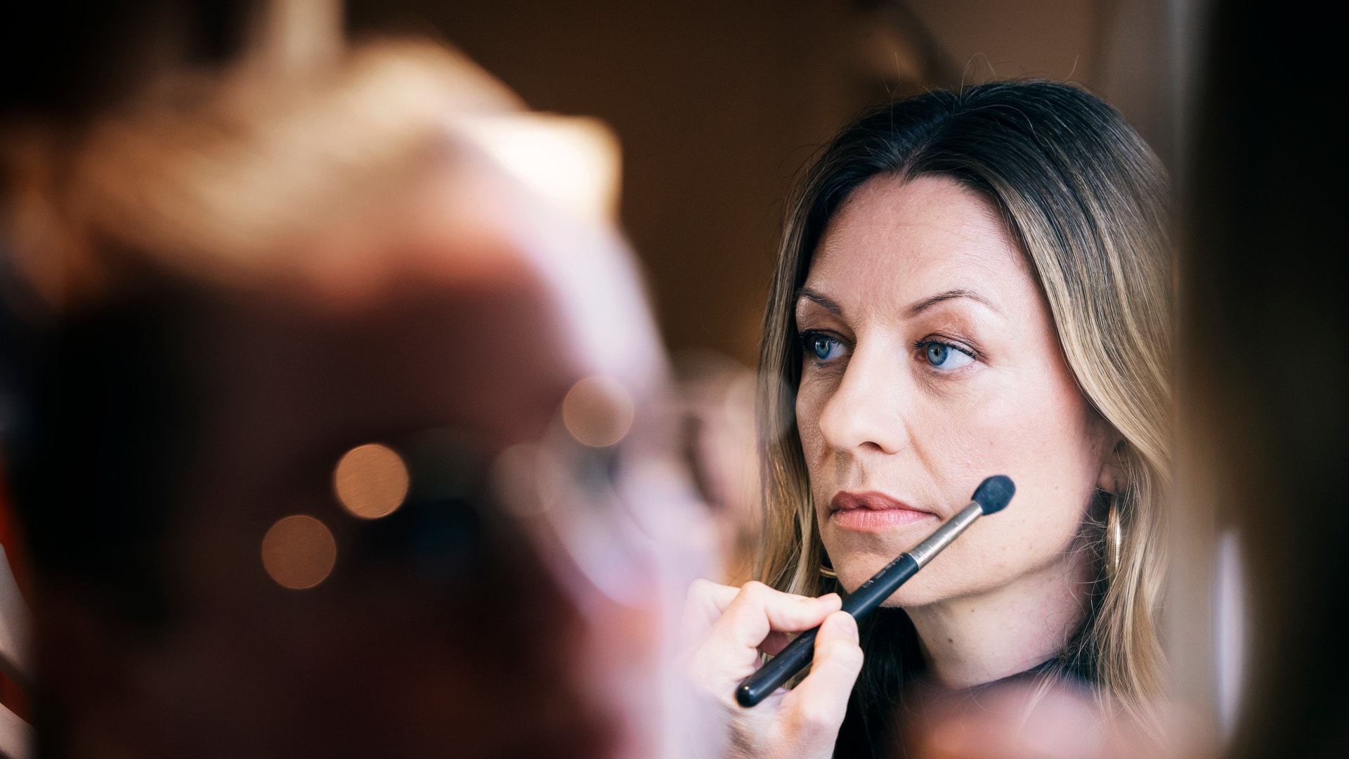 Kvinna får makeup applicerad med en makeuppensil på kinden.