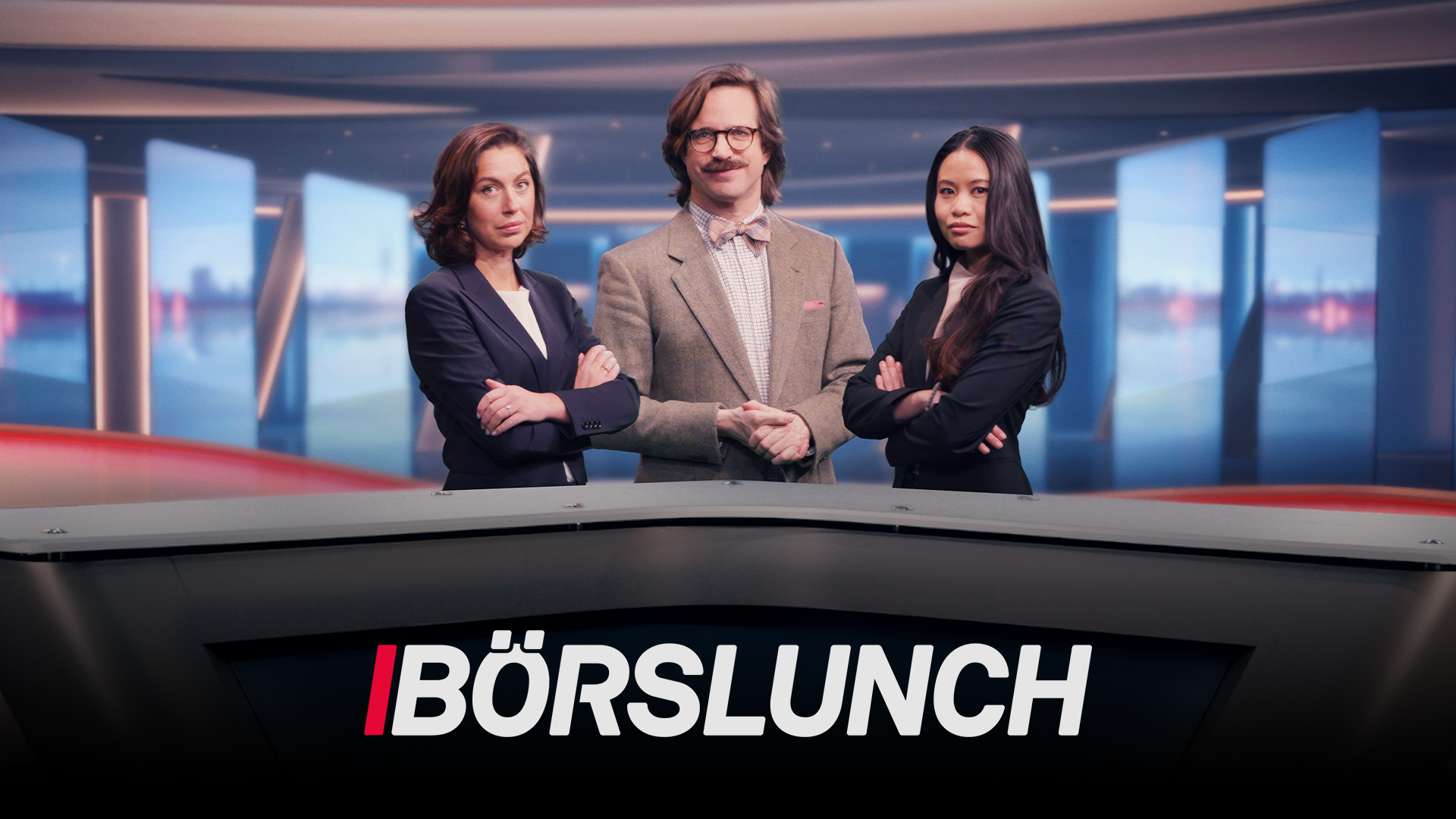 Tre programledare står framför en modern studiobakgrund med blå toner och höga fönster. En man i mitten bär glasögon och beige blazer, flankerad av två kvinnor i mörka kostymjackor. Alla tre står med armarna i kors. Texten "BÖRSLUNCH" visas i vitt och rött längst ned på bilden.