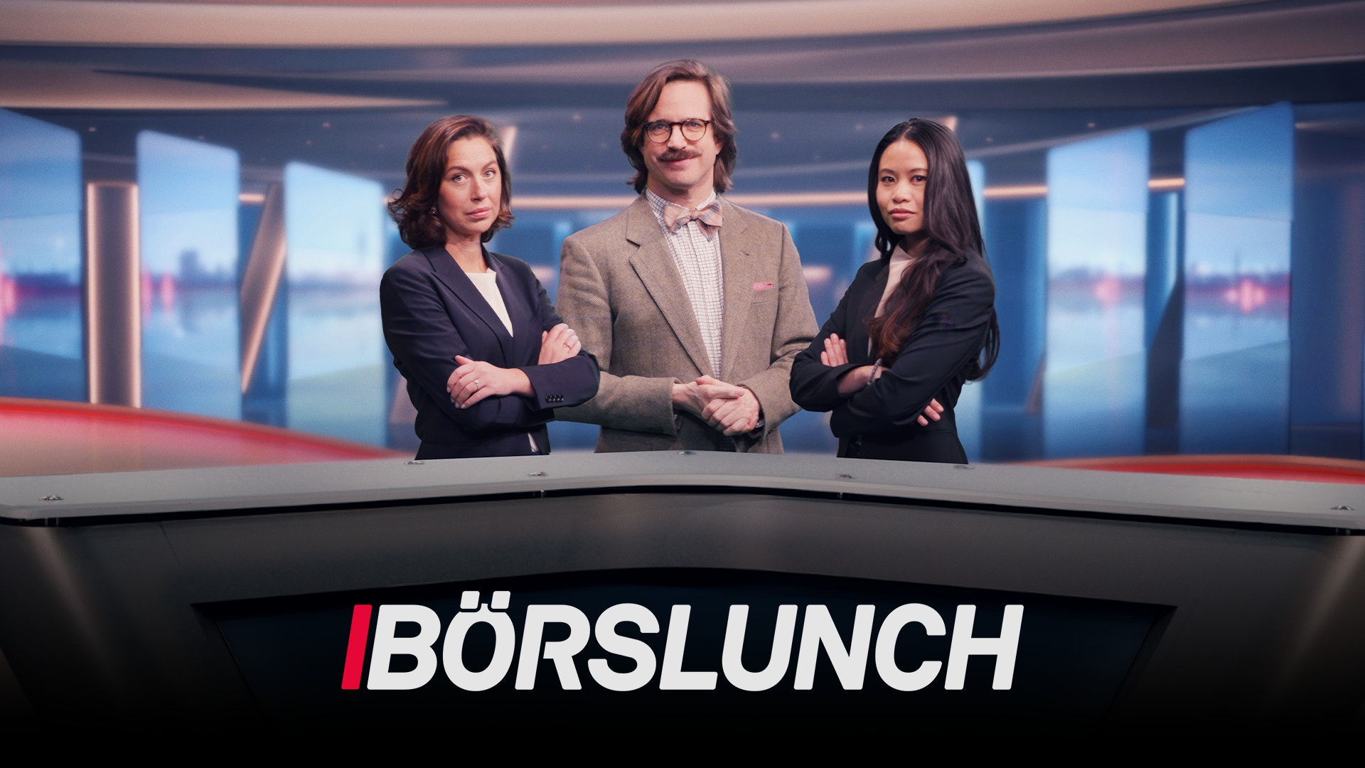 Tre programledare står framför en modern studiobakgrund med blå toner och höga fönster. En man i mitten bär glasögon och beige blazer, flankerad av två kvinnor i mörka kostymjackor. Alla tre står med armarna i kors. Texten "BÖRSLUNCH" visas i vitt och rött längst ned på bilden.