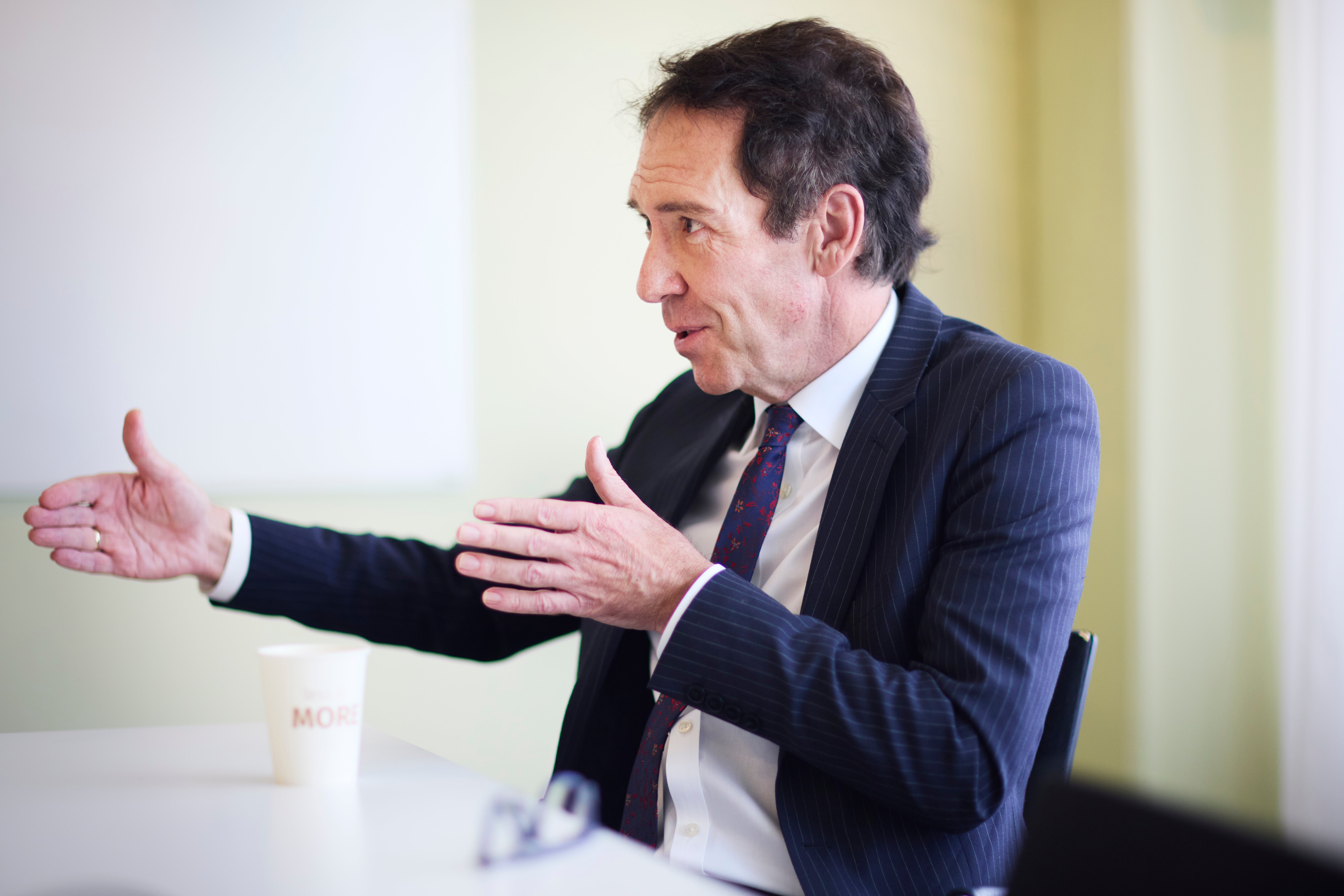 Byron Sharp är fotograferad i profil, sittandes vid ett bord och gestikulerandes med händerna.