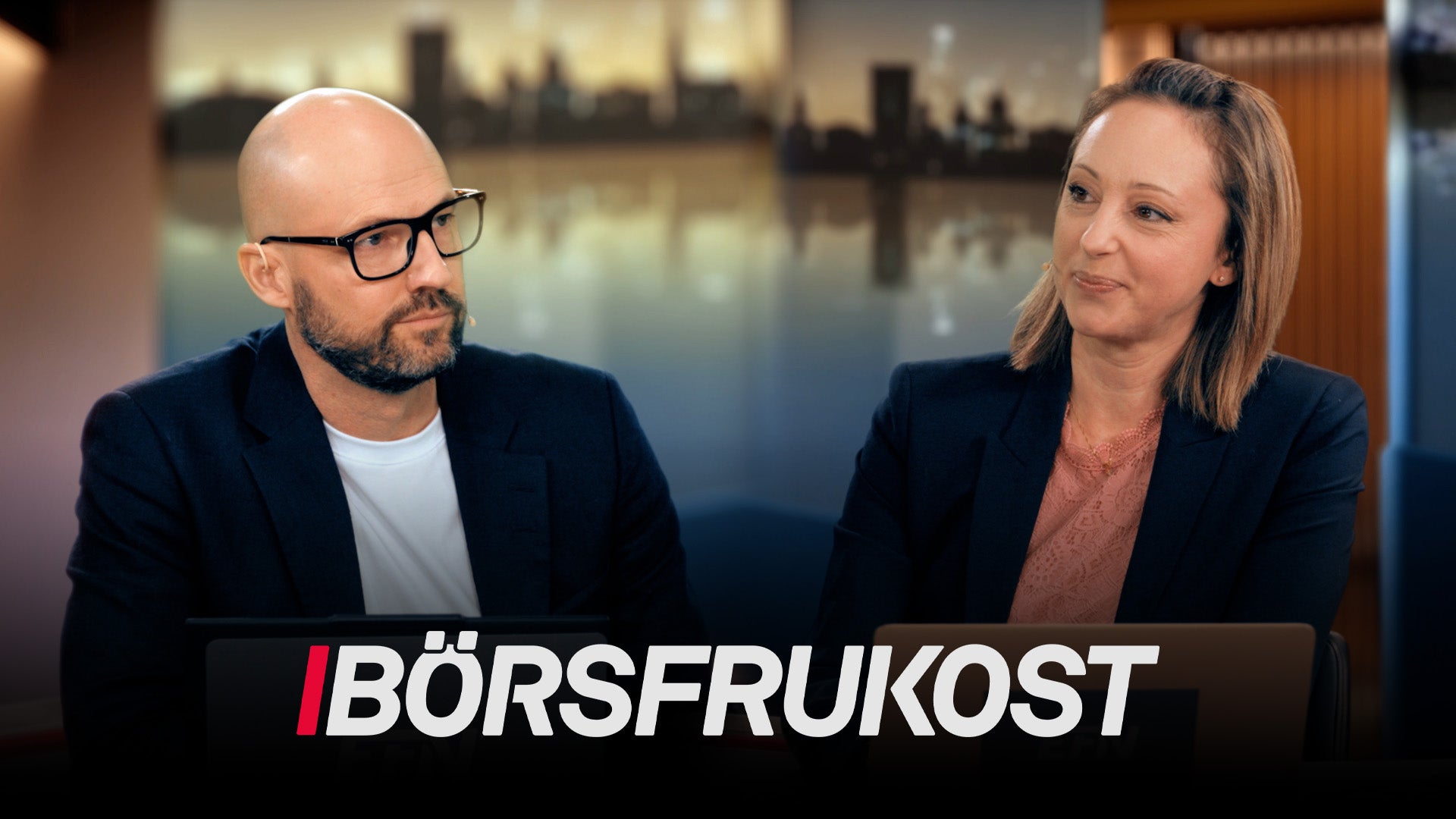 Två personer i affärskläder sitter vid ett bord och diskuterar under en event kallad Börsfrukost.