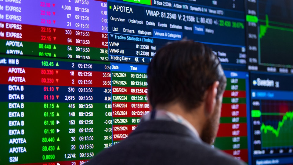 Person tittar på finansiell data och aktiekurser på en datorskärm