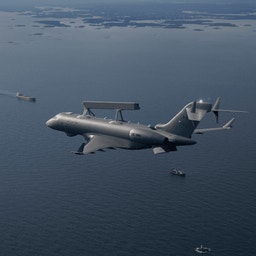 Militärt övervakningsflygplan flyger över havet med fartyg synliga under sig.
