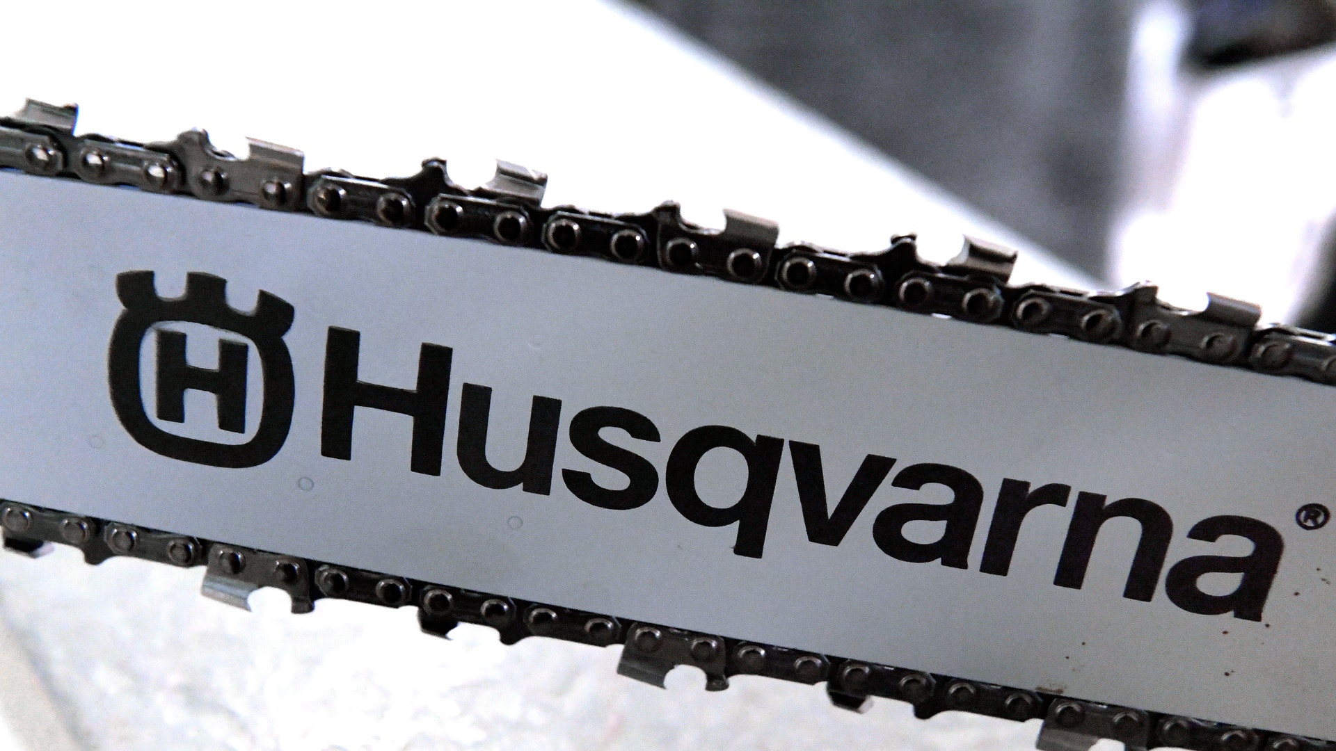 Närbild på en motorsågskedja och styrsvärd med Husqvarnas logotyp.