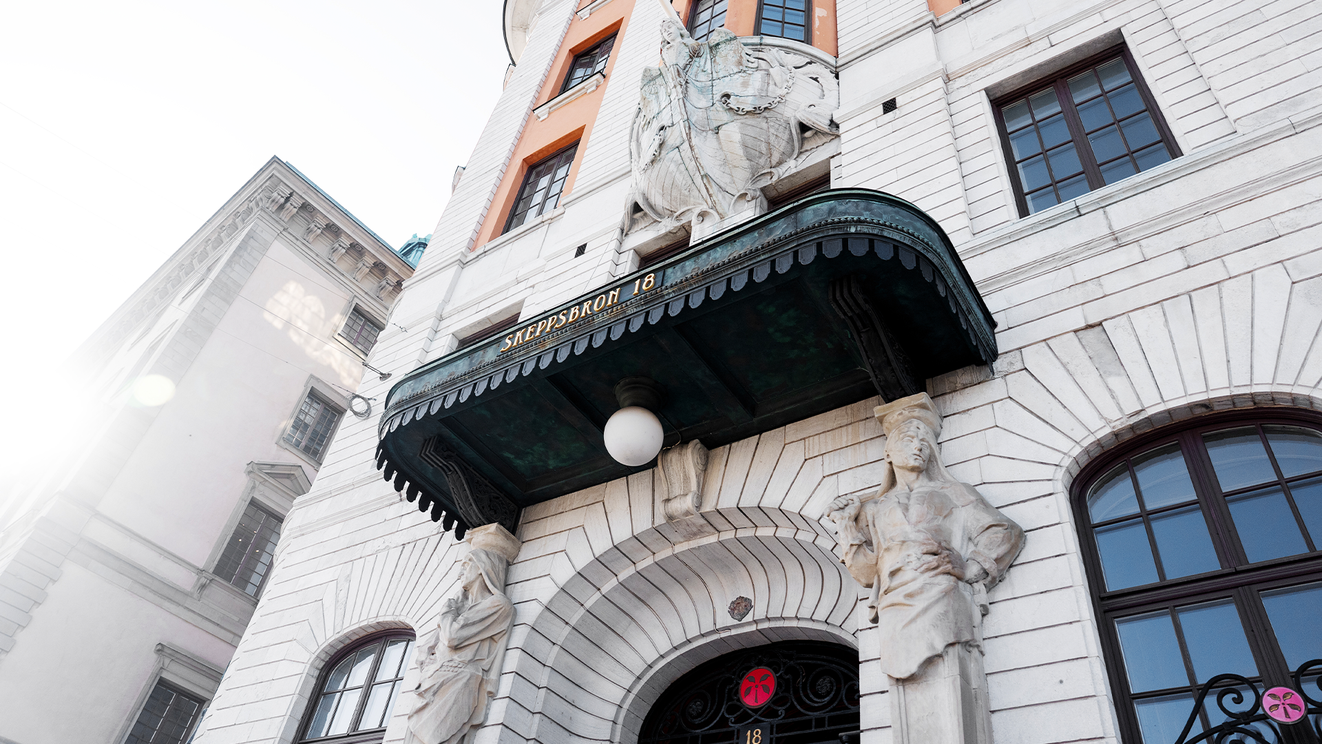 Klassisk byggnadsfasad med vita stendetaljer, dekorativ baldakin och fönster