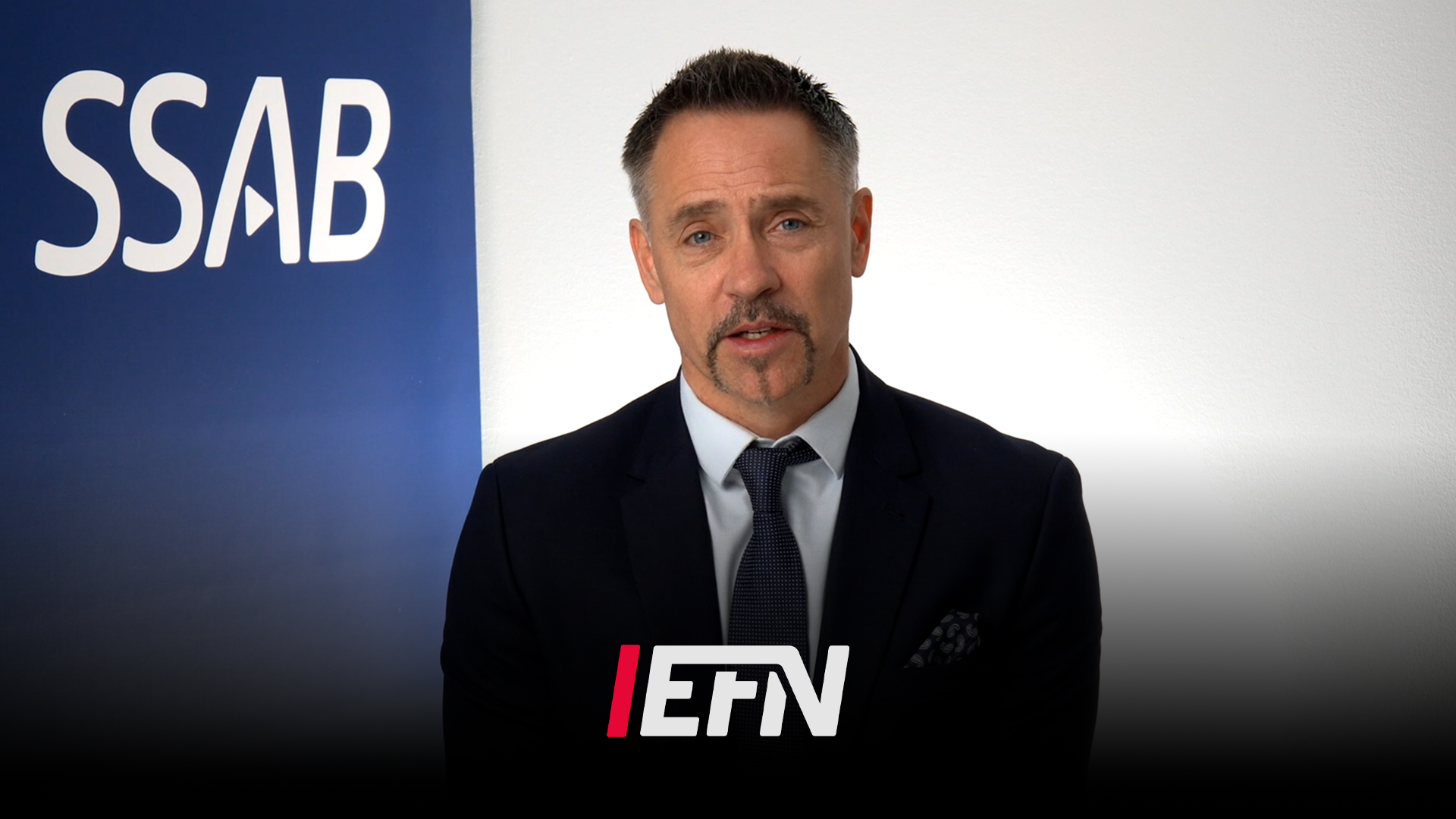 Porträtt av en man i mörkblå kostym och slips framför SSAB och EFN-logotyper.