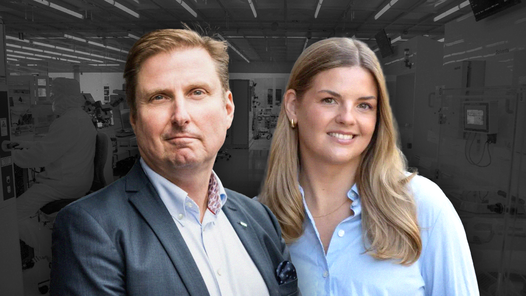 Två personer i professionell kläder poserar tillsammans framför en industriell bakgrund.