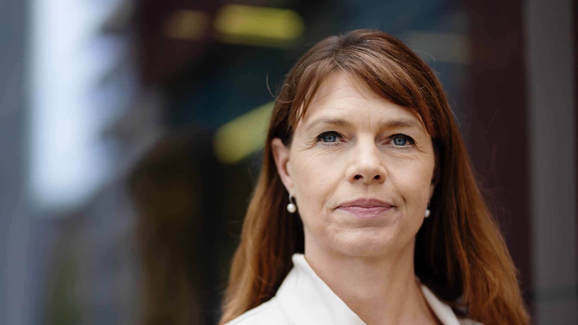 Porträtt av en kvinna med långt rödbrunt hår och vit skjorta.