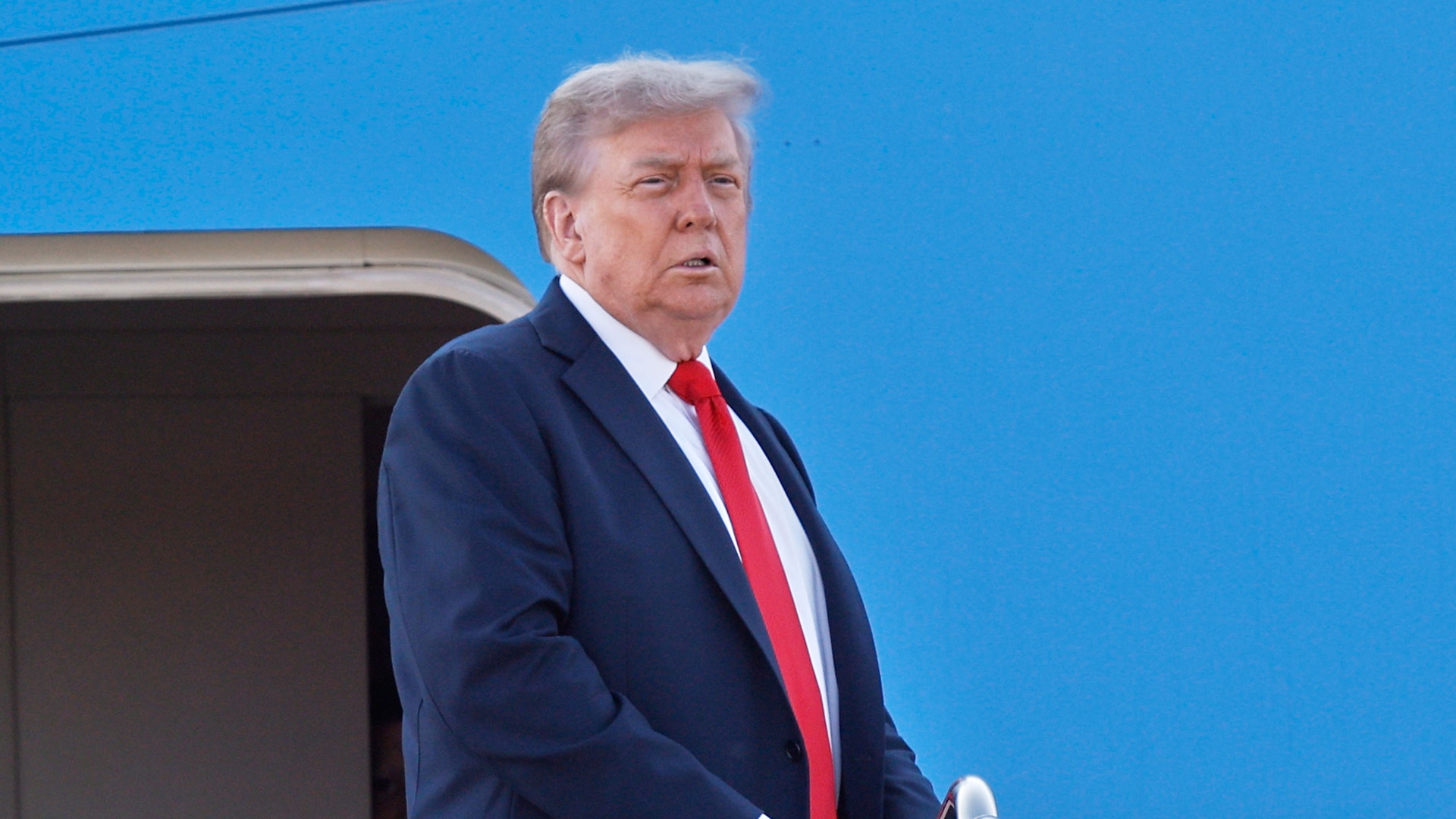 Trump utanför Air Force One klädd i kostym på väg till Alaska för toppmötet med Putin.