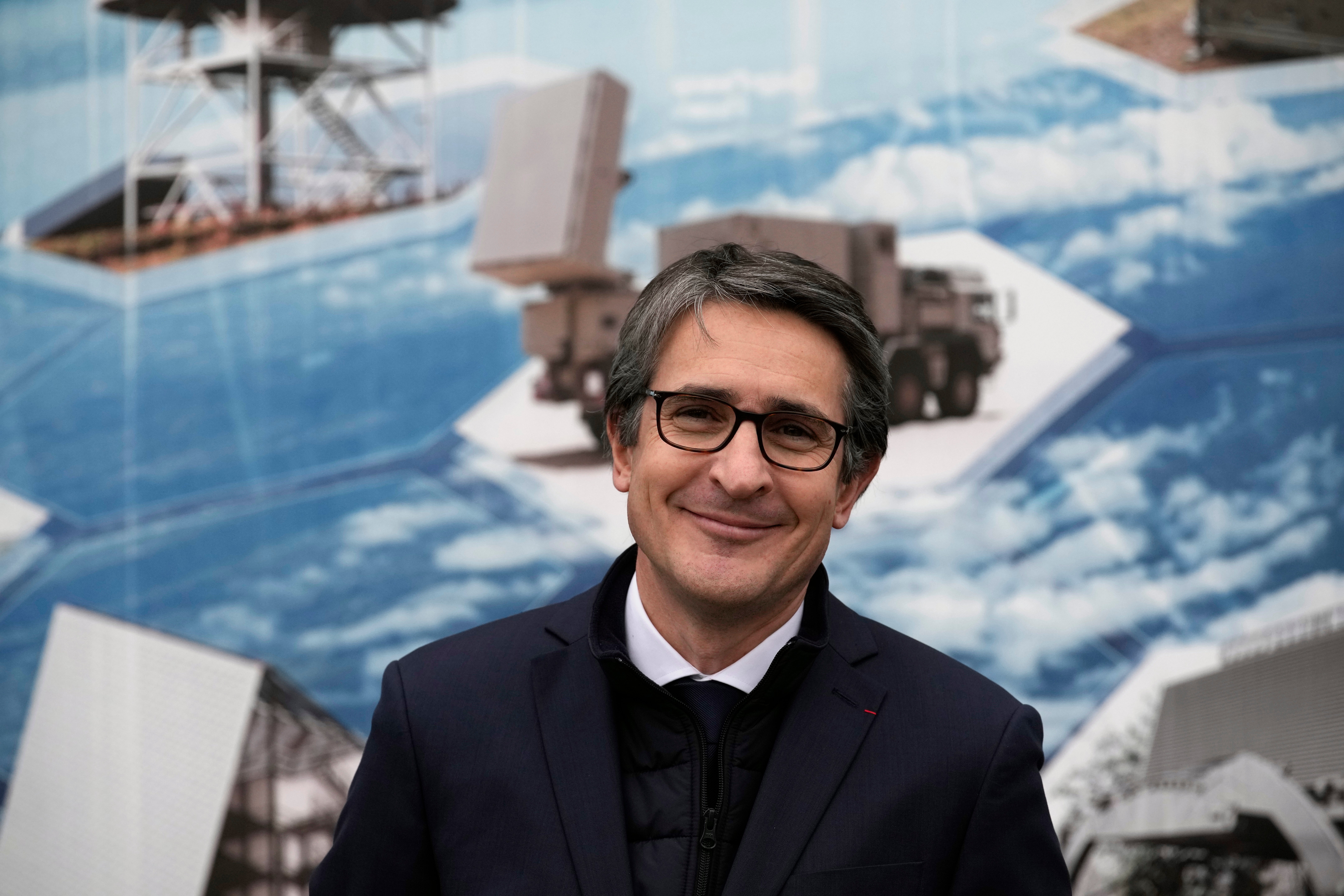 Porträtt av en man i kostym framför en bakgrund med bilder av fartyg och hav.