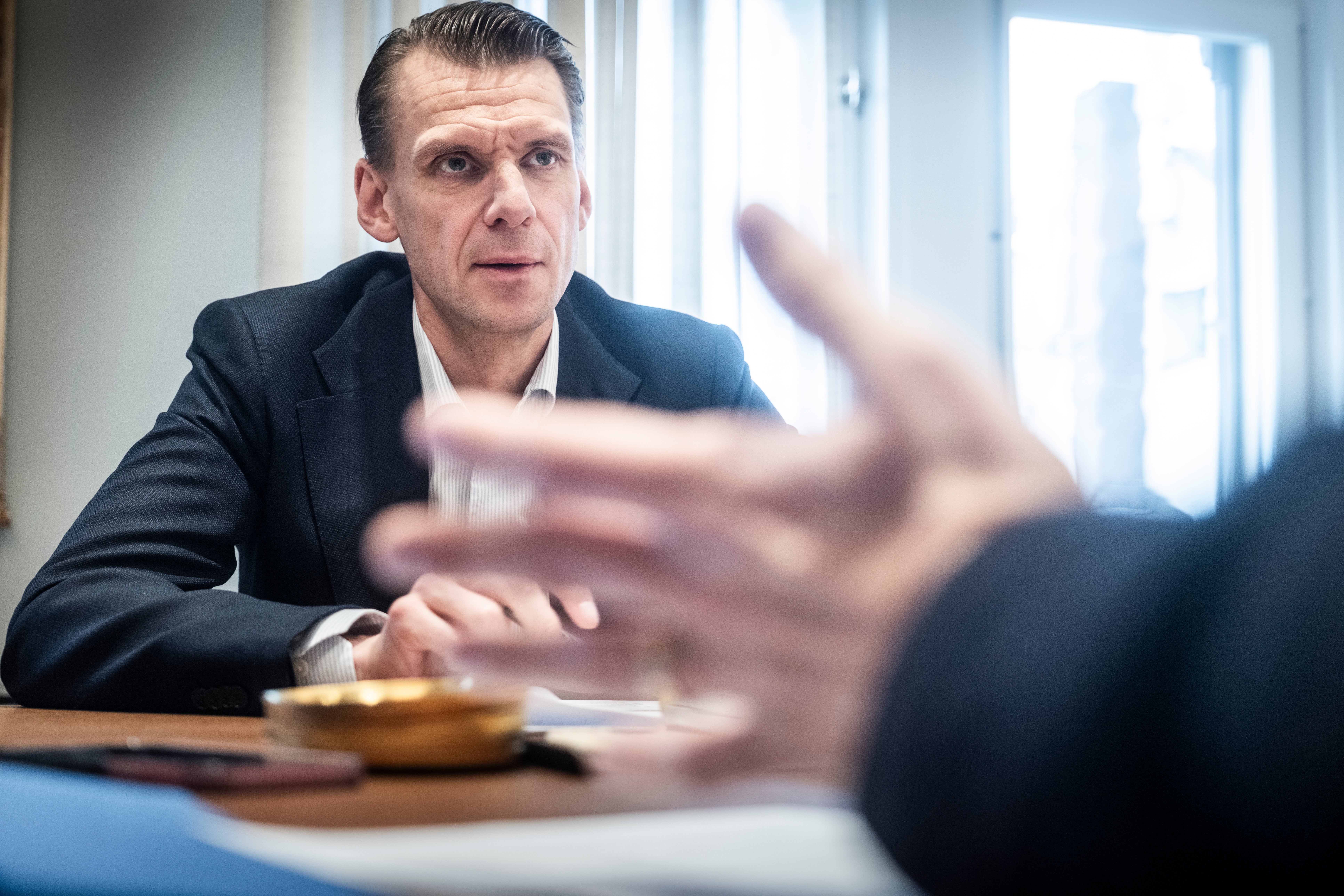Christian Cederholm, vd för Investor, sitter i mörk kavaj vid ett bord under ett samtal. I förgrunden syns en suddig hand som gestikulerar.