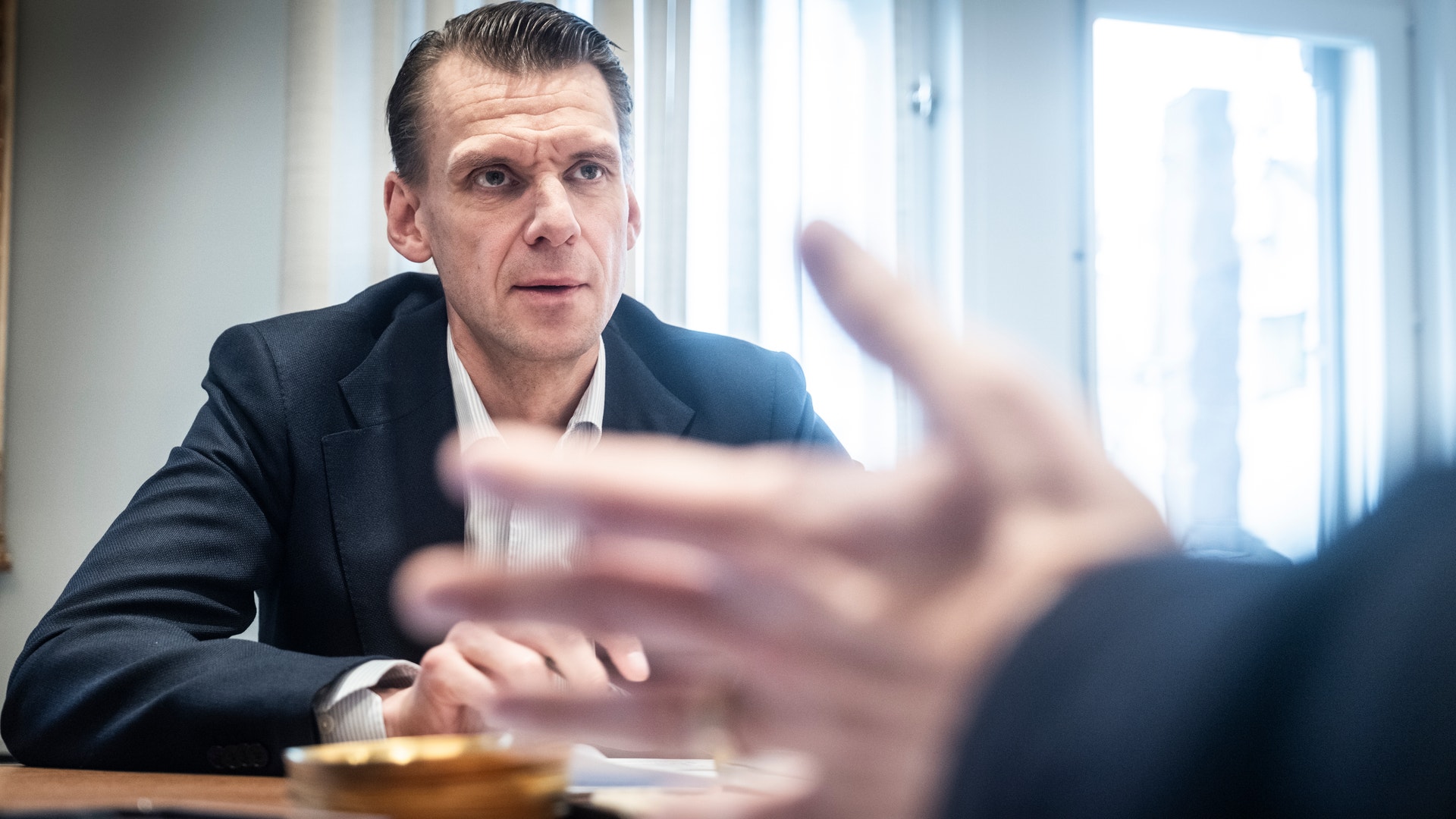 Christian Cederholm, vd för Investor, sitter i mörk kavaj vid ett bord under ett samtal. I förgrunden syns en suddig hand som gestikulerar.