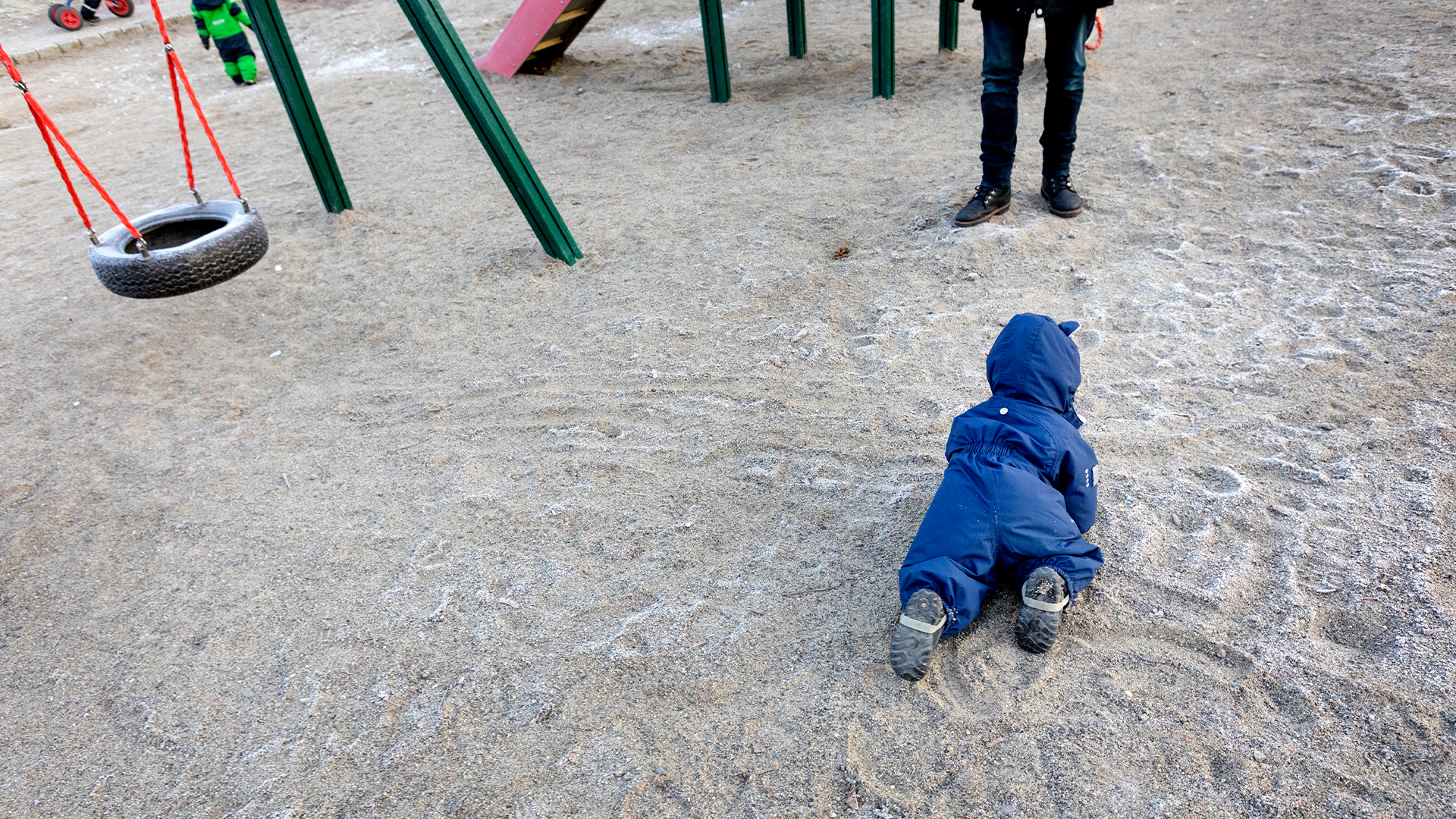 Barn kryper på lekplats vid förskola. 