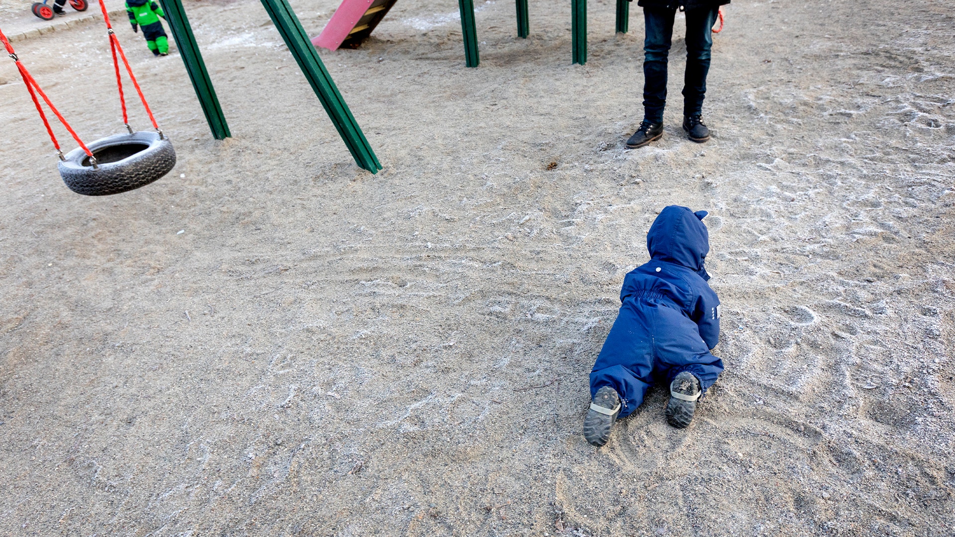 Barn kryper på lekplats vid förskola.