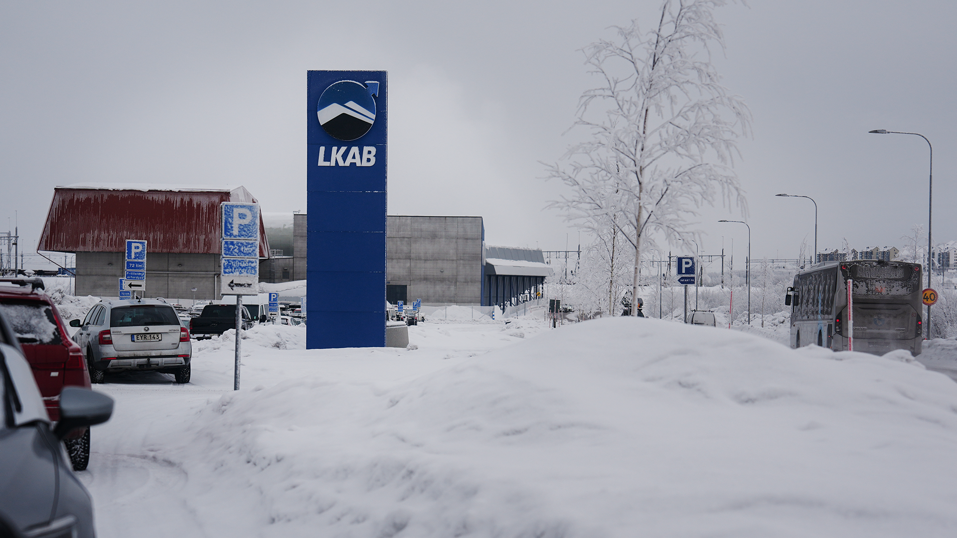 Snöig parkeringsplats med LKAB-skylt och industribyggnader i vinterlandskap