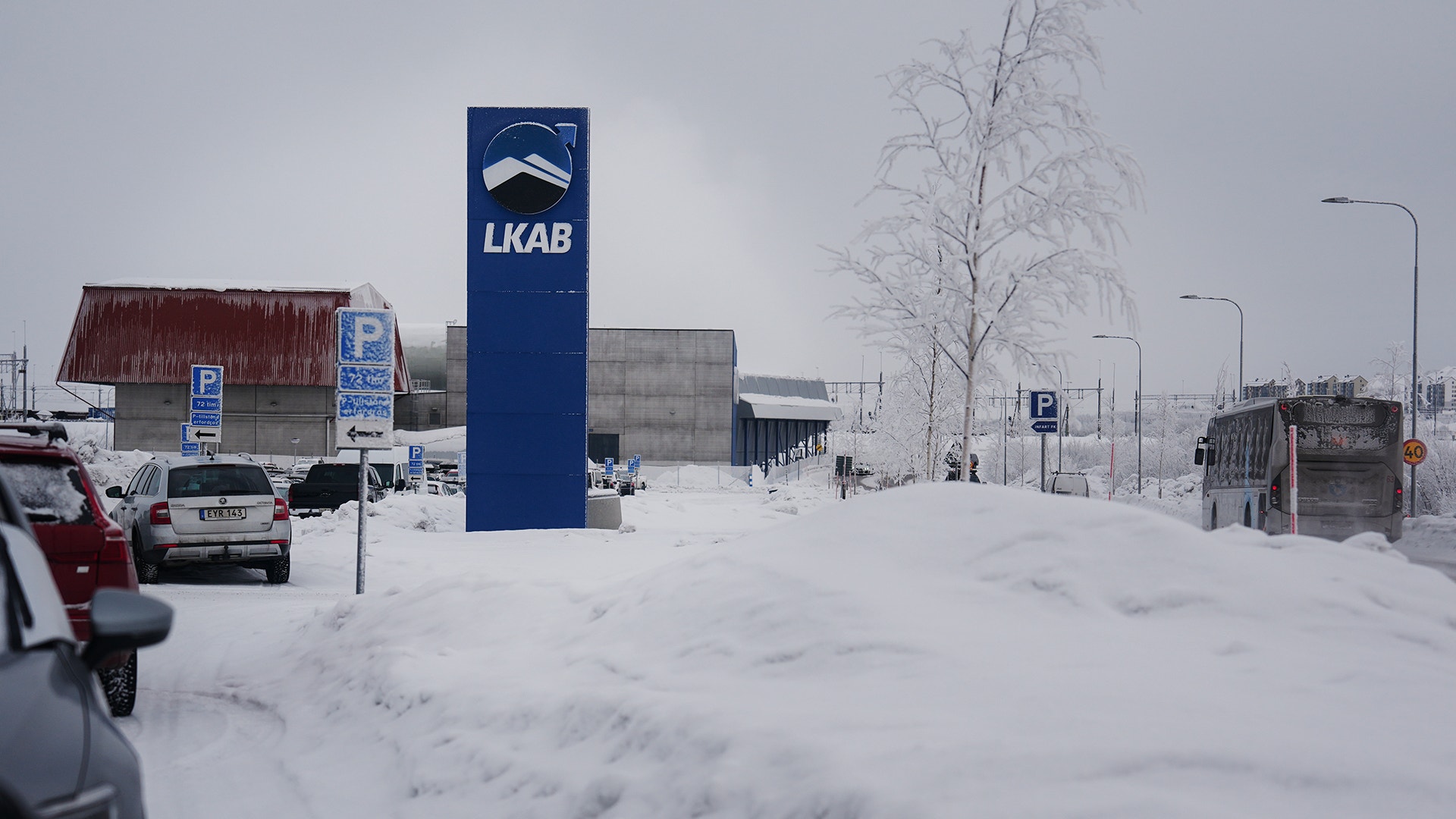 Snöig parkeringsplats med LKAB-skylt och industribyggnader i vinterlandskap