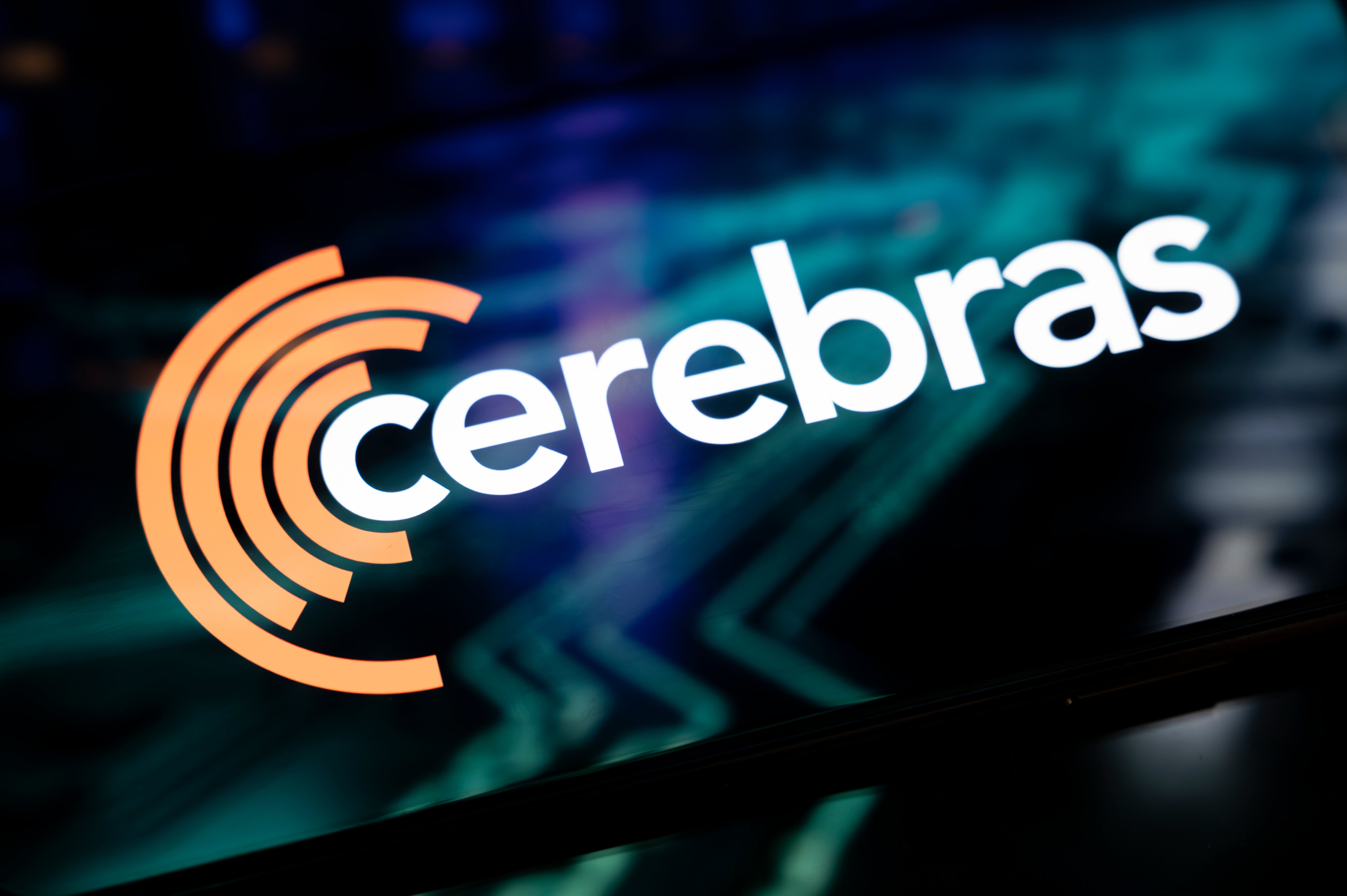 Cerebras-logotypen med orange koncentriska cirklar och vit text på en teknisk bakgrund med blå och gröna nyanser.