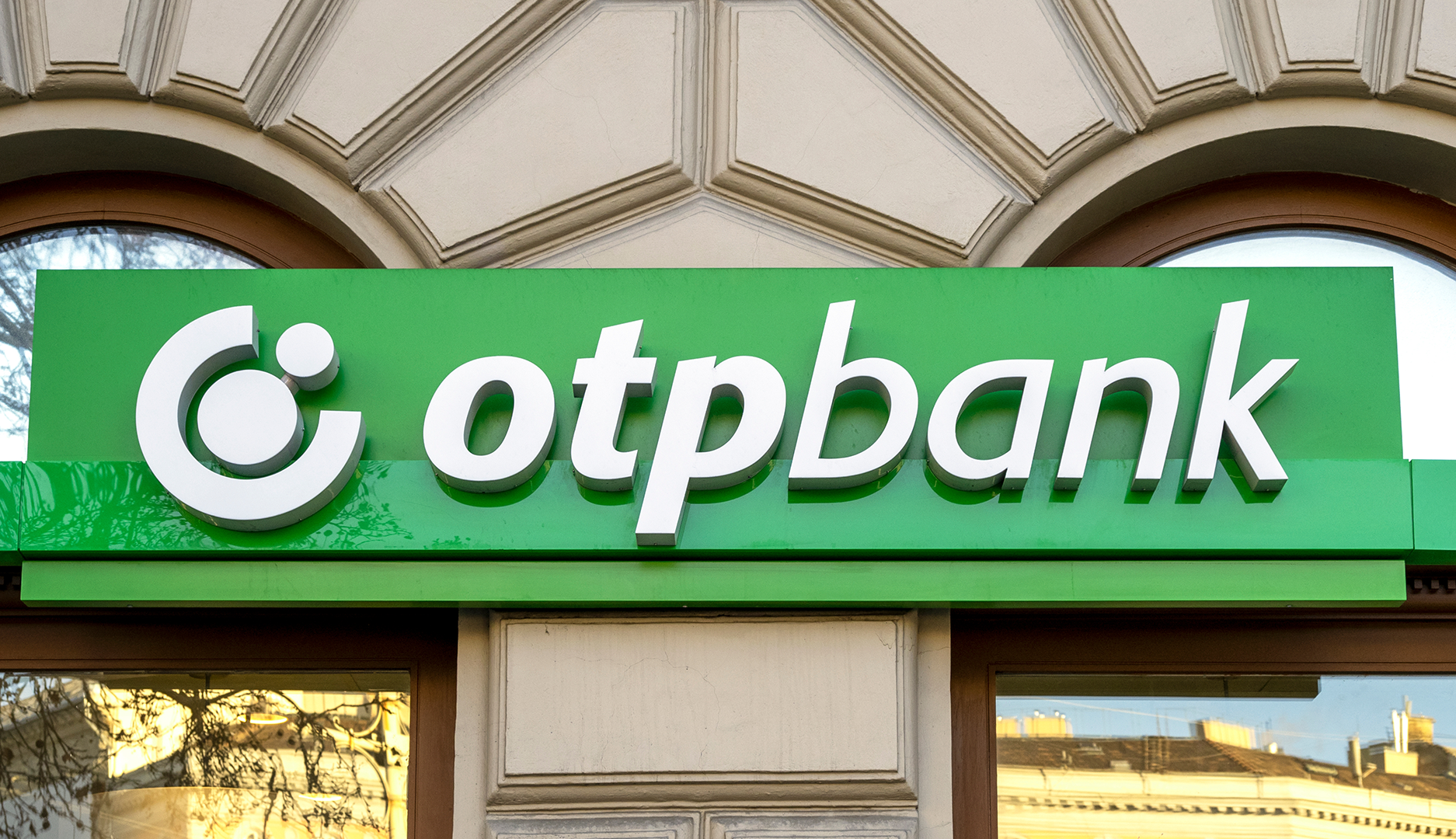 En grön skylt med texten "OTP Bank" på en byggnadsfasad.