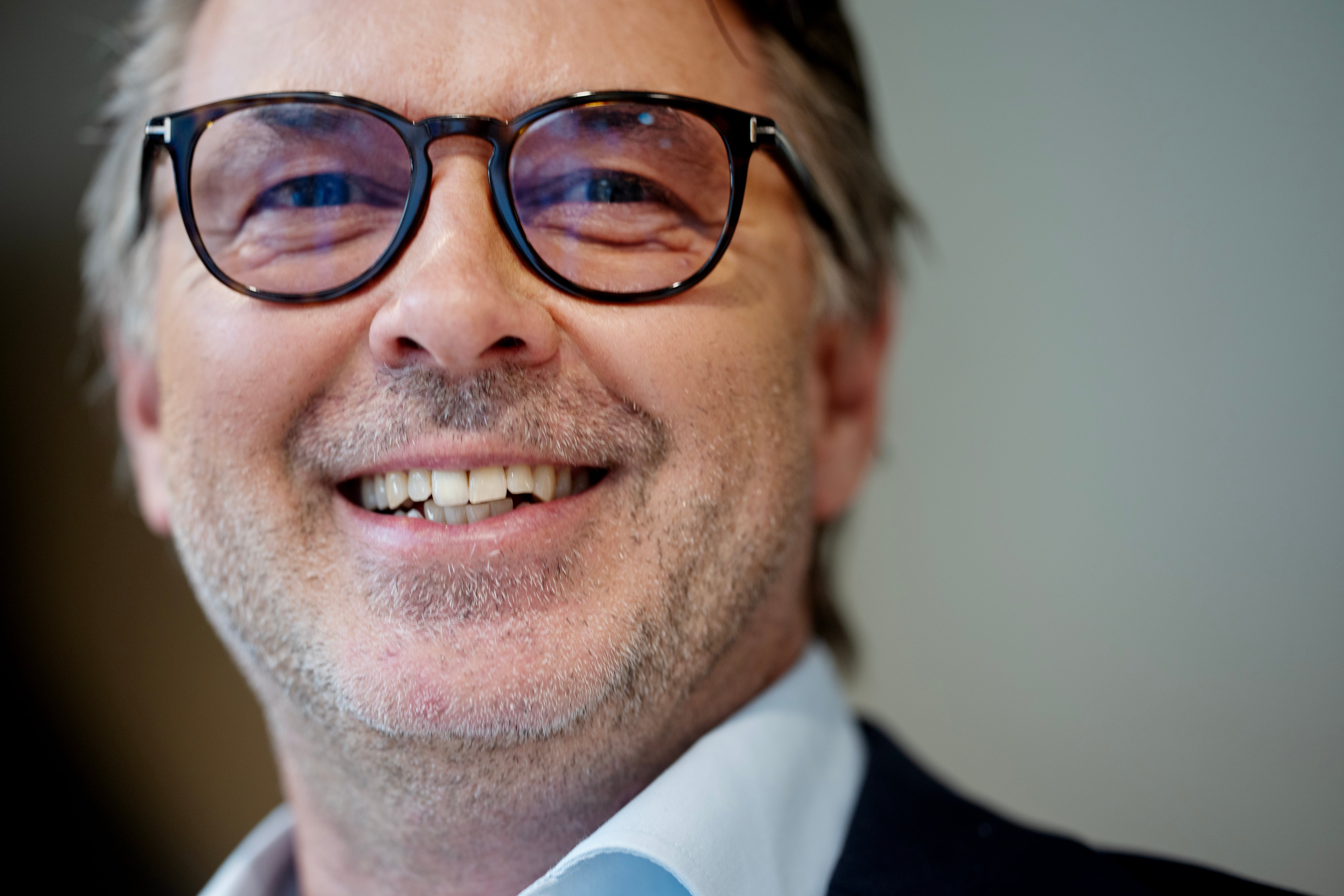 Porträtt av en man med glasögon som ler mot kameran