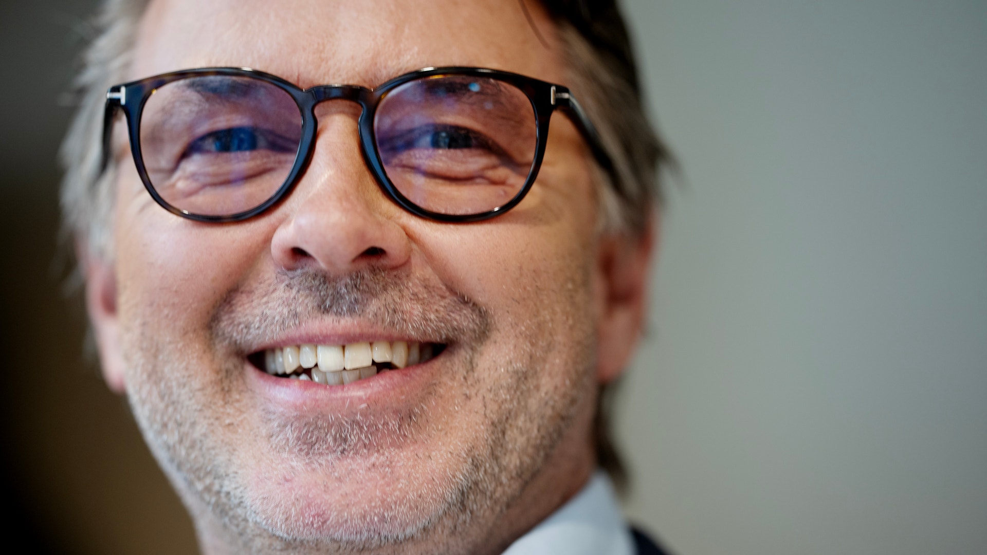 Porträtt av en man med glasögon som ler mot kameran