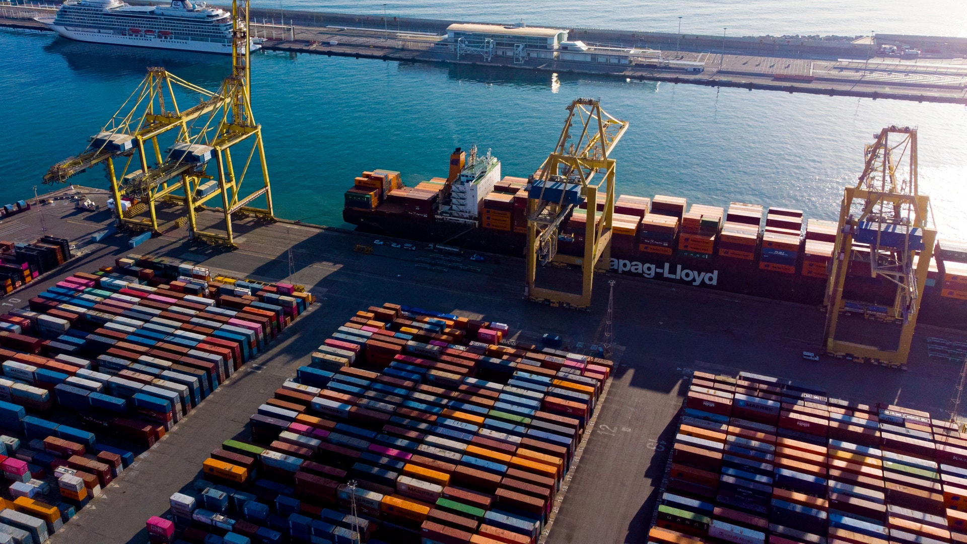Flera containerfartyg som ligger vid en hamn, där container lassas på.