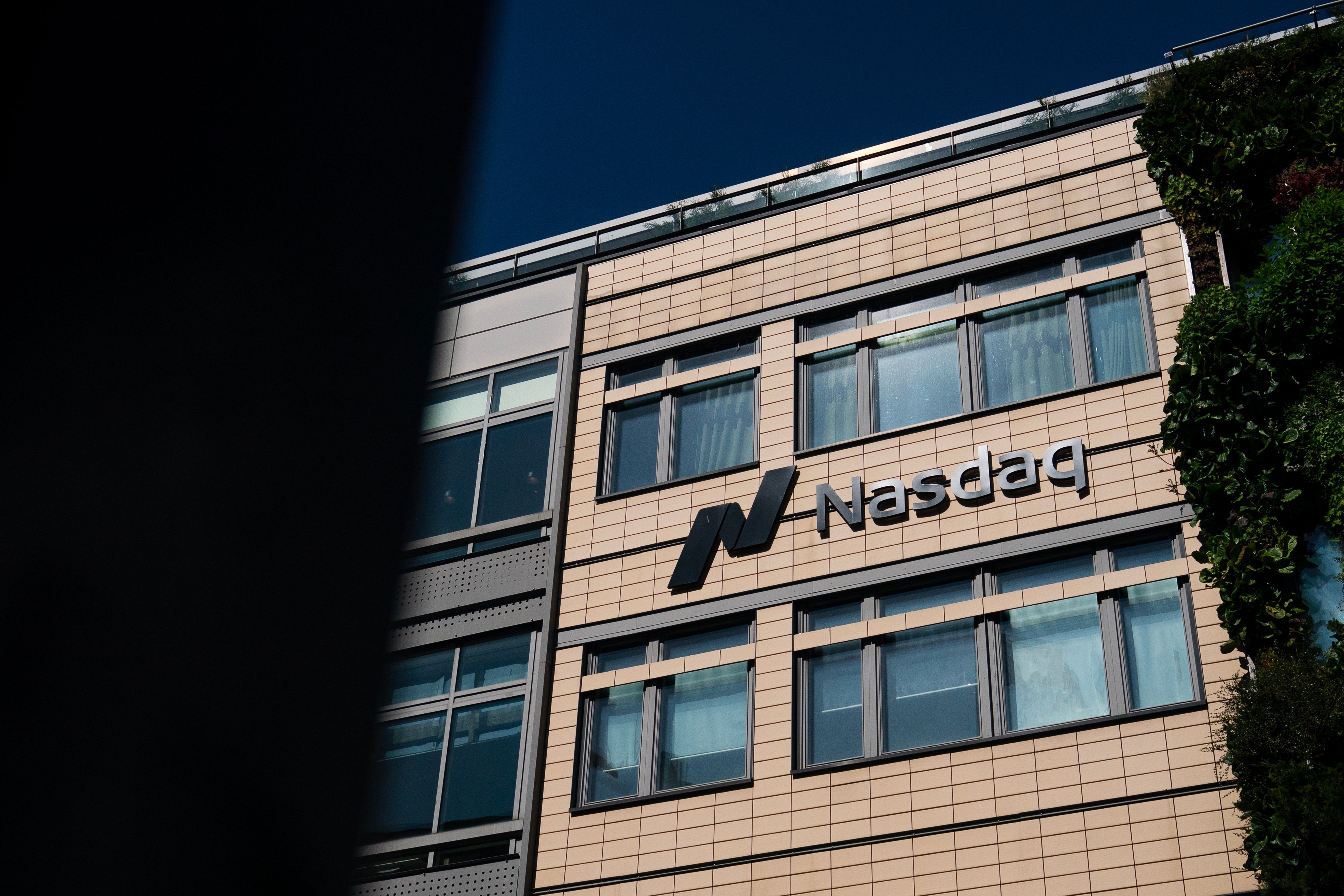 Fasad på en modern kontorsbyggnad med Nasdaq-logon. Byggnaden är klädd i ljus sten med många fönster.