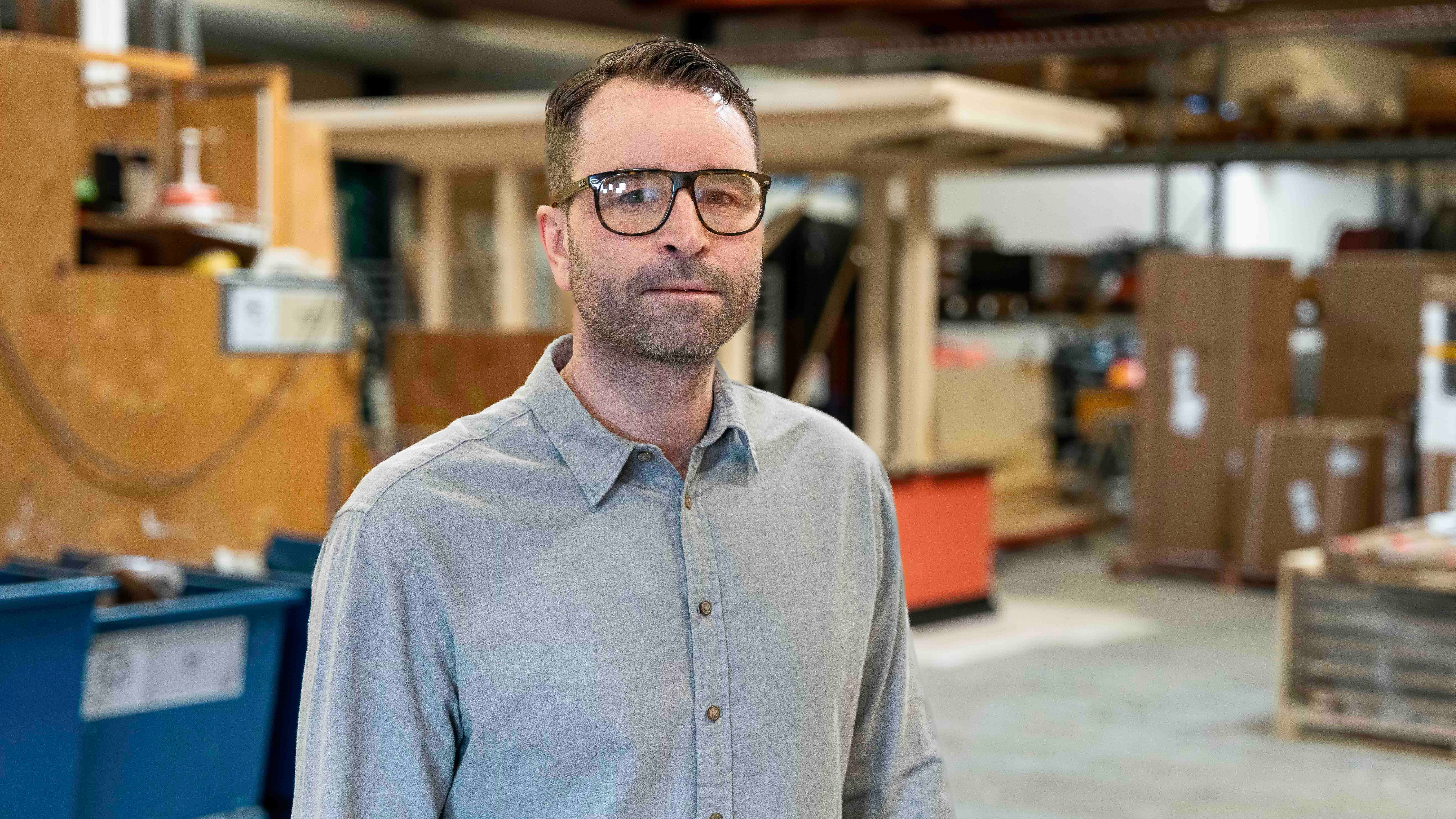 Porträtt av man med glasögon och ljusblå skjorta i en verkstad